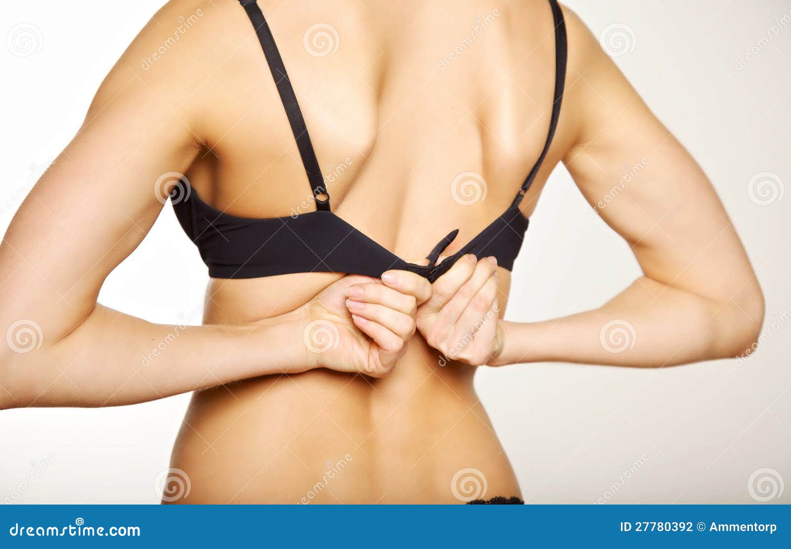 Woman unhooking bra on bed - Stock Photo - Dissolve