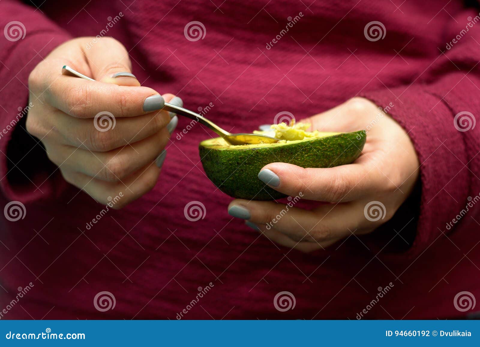Woman Use a Spoon To Scoop the Avocado Out of the Shell Stock Photo
