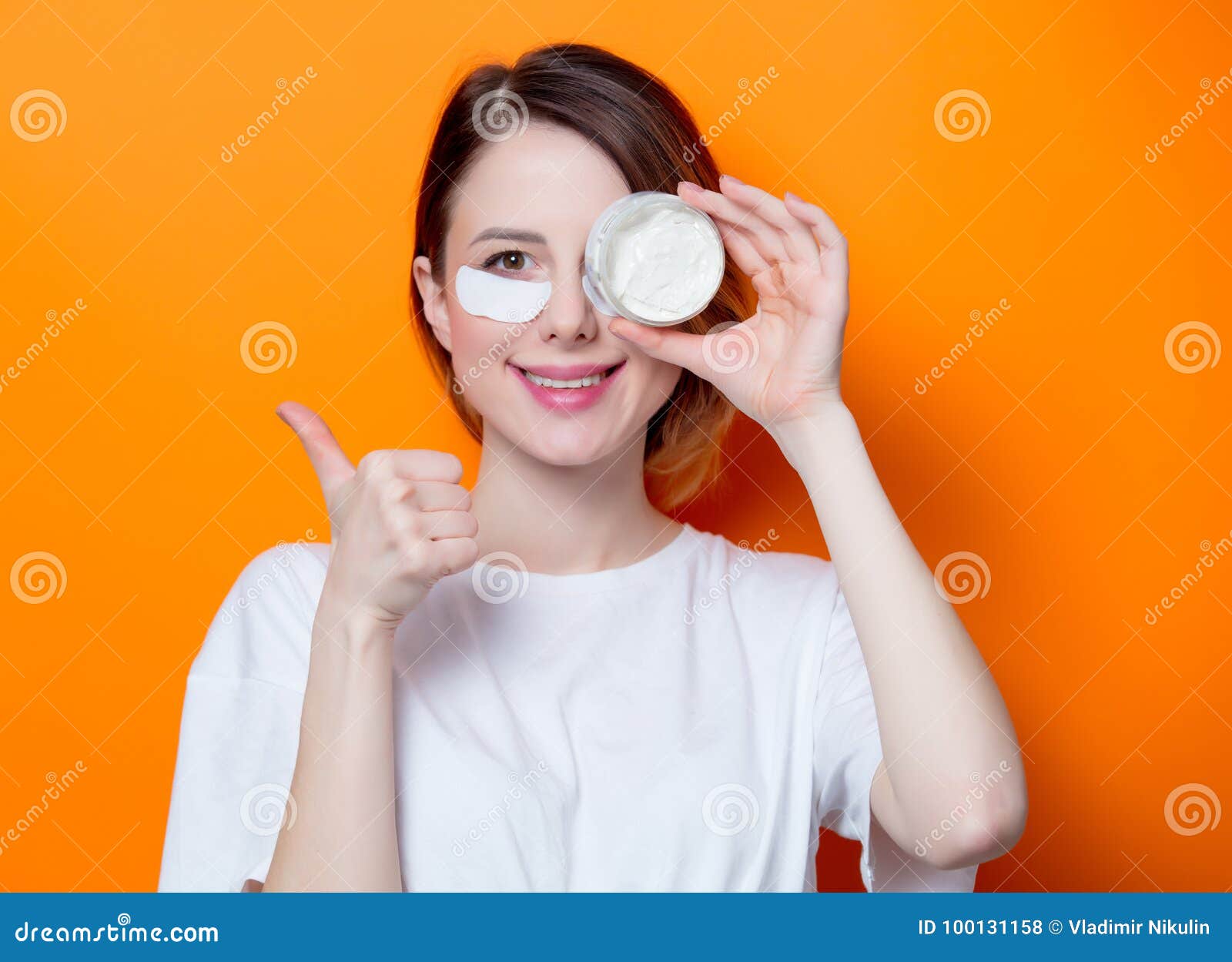 woman using eye patch for her eyes and holding cream