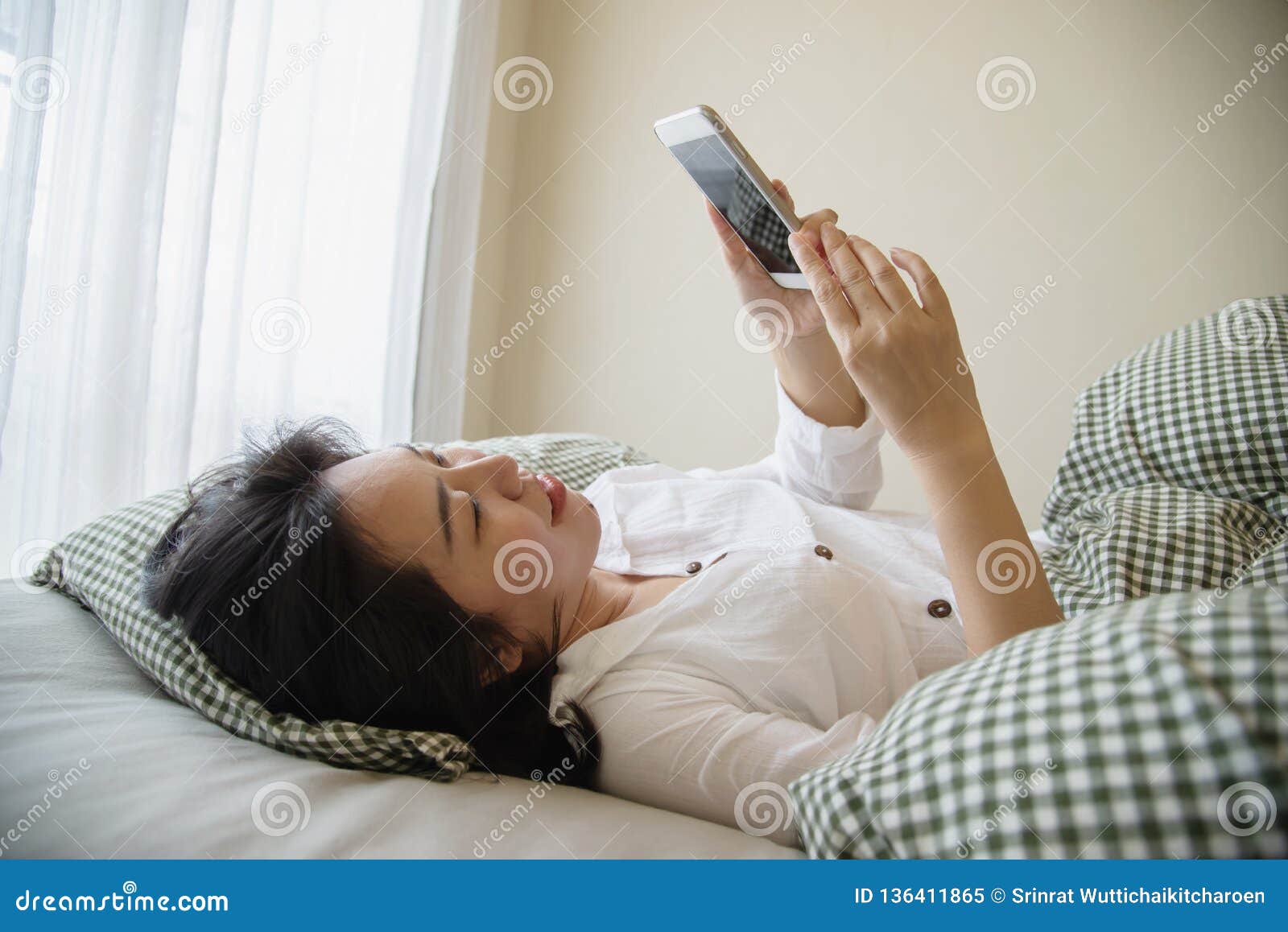 Woman Using Mobile Phone While Wake Up On Bed In The Morning