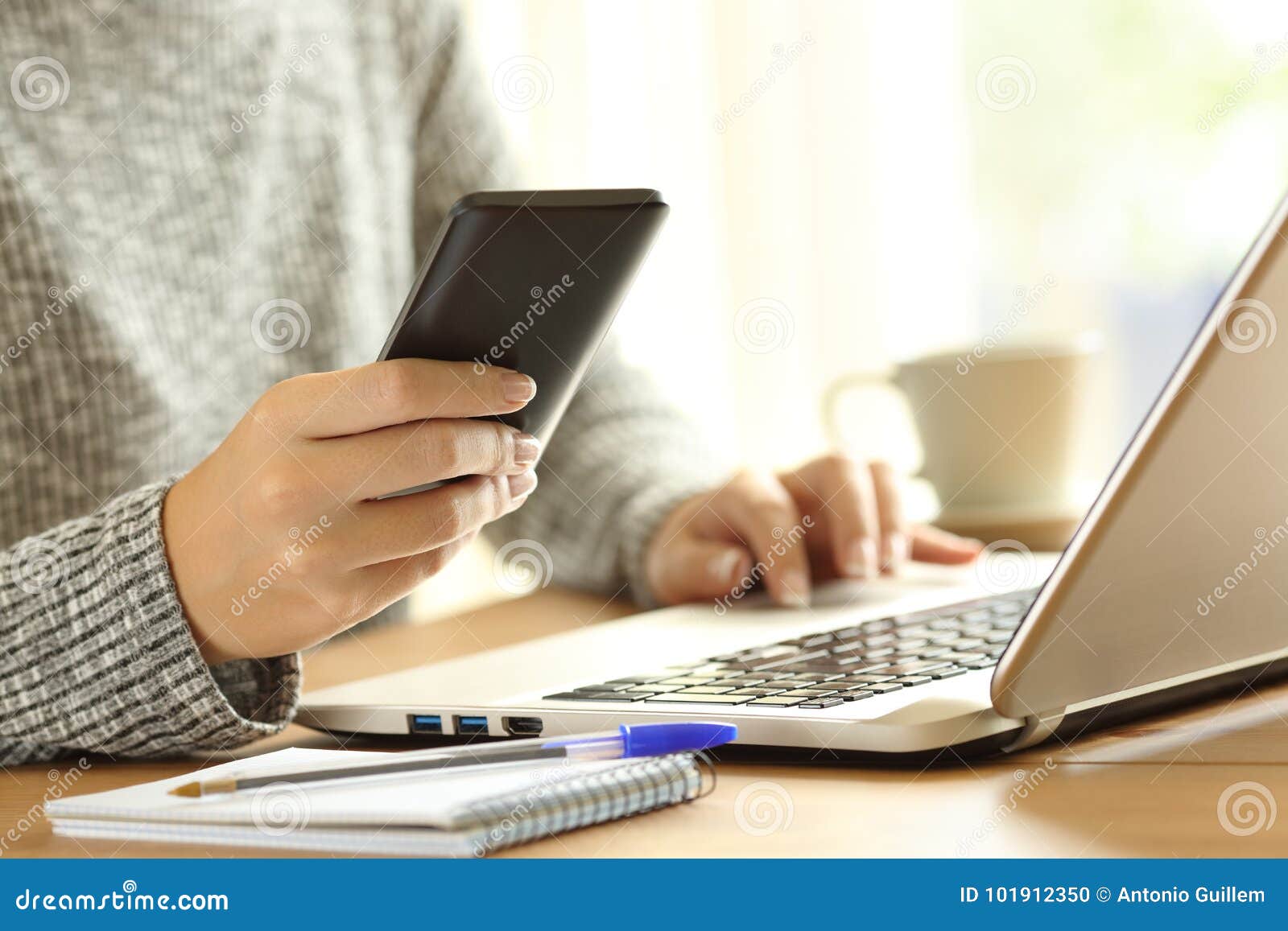 woman using a phone and a laptop on a table