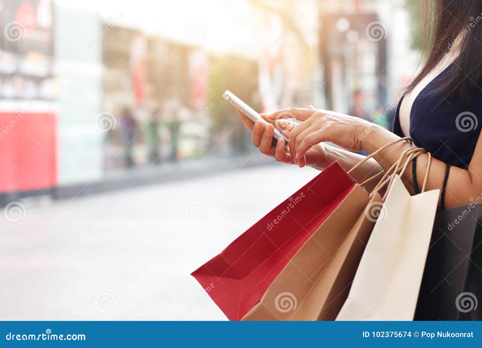 woman using smartphone while holding shopping bags