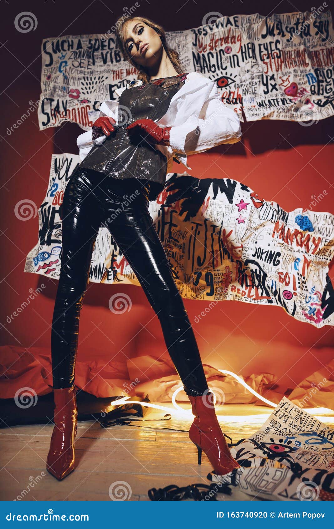 Woman in Vinyl Black Pants and Glossy Top on Art Red Background Stock ...