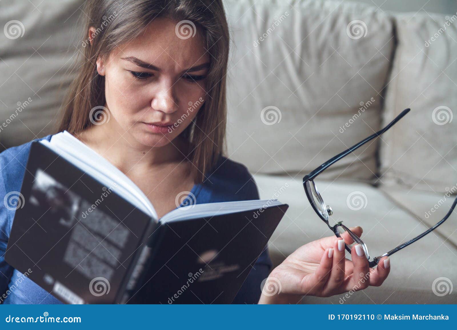 A Woman with Vision Problems is Reading a Book with Glasses Stock Photo