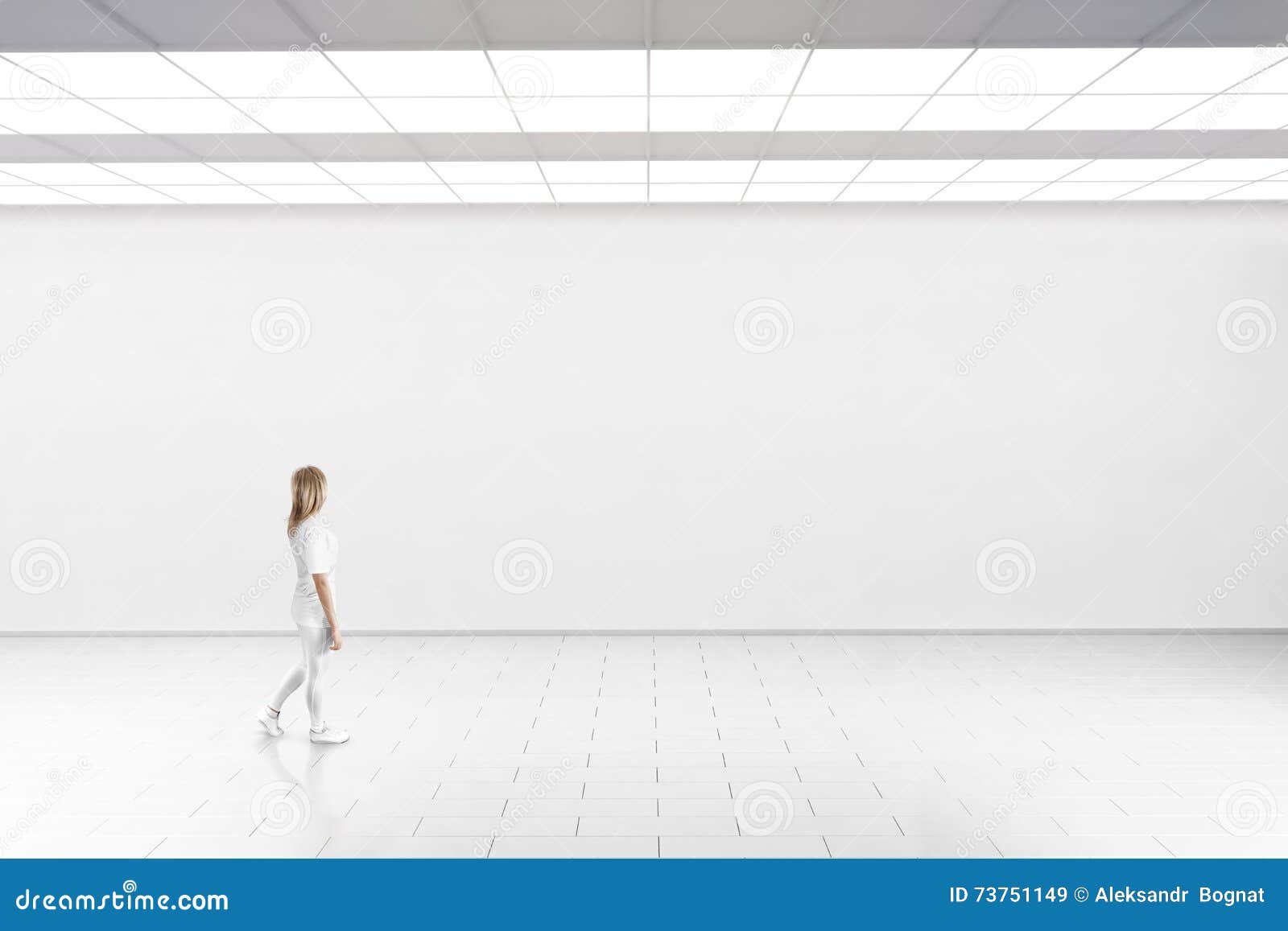 woman walk in museum gallery with blank wall.