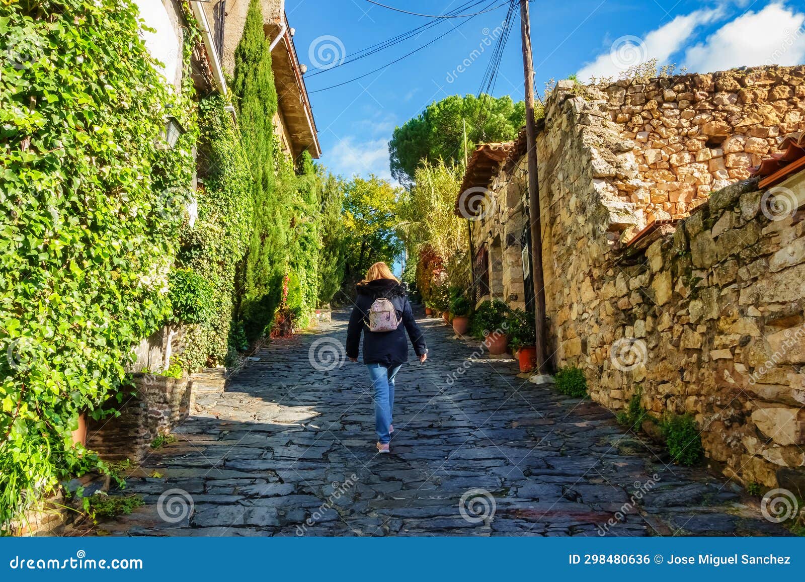 woman walking up a sloping street in the old stone village, patones de arriba.