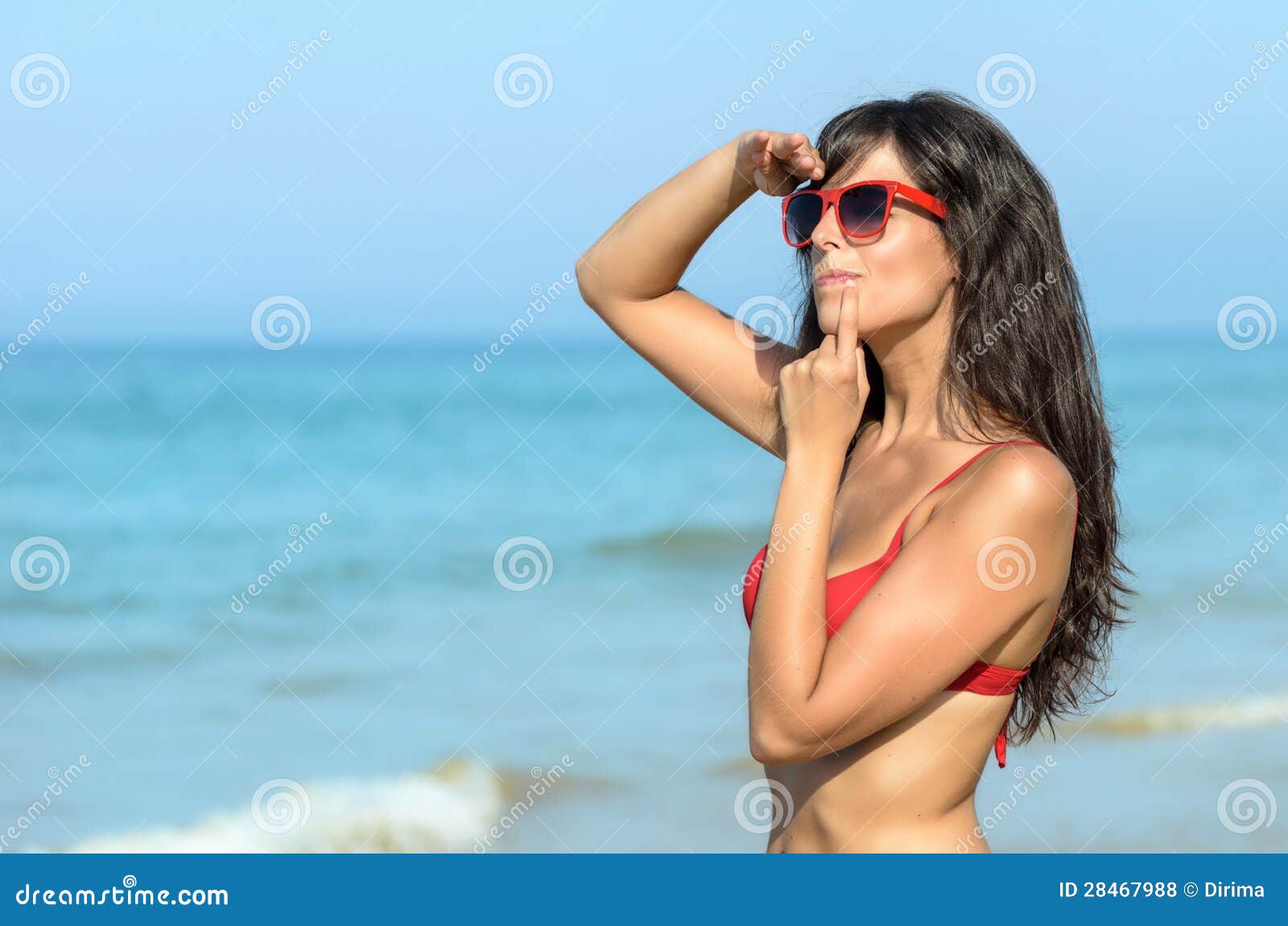 Woman watching and looking for someone in the beach. Worried woman on the beach watching in the sea. beautiful brunette caucasian model with red sunglasses looking for someone. Copyspace.