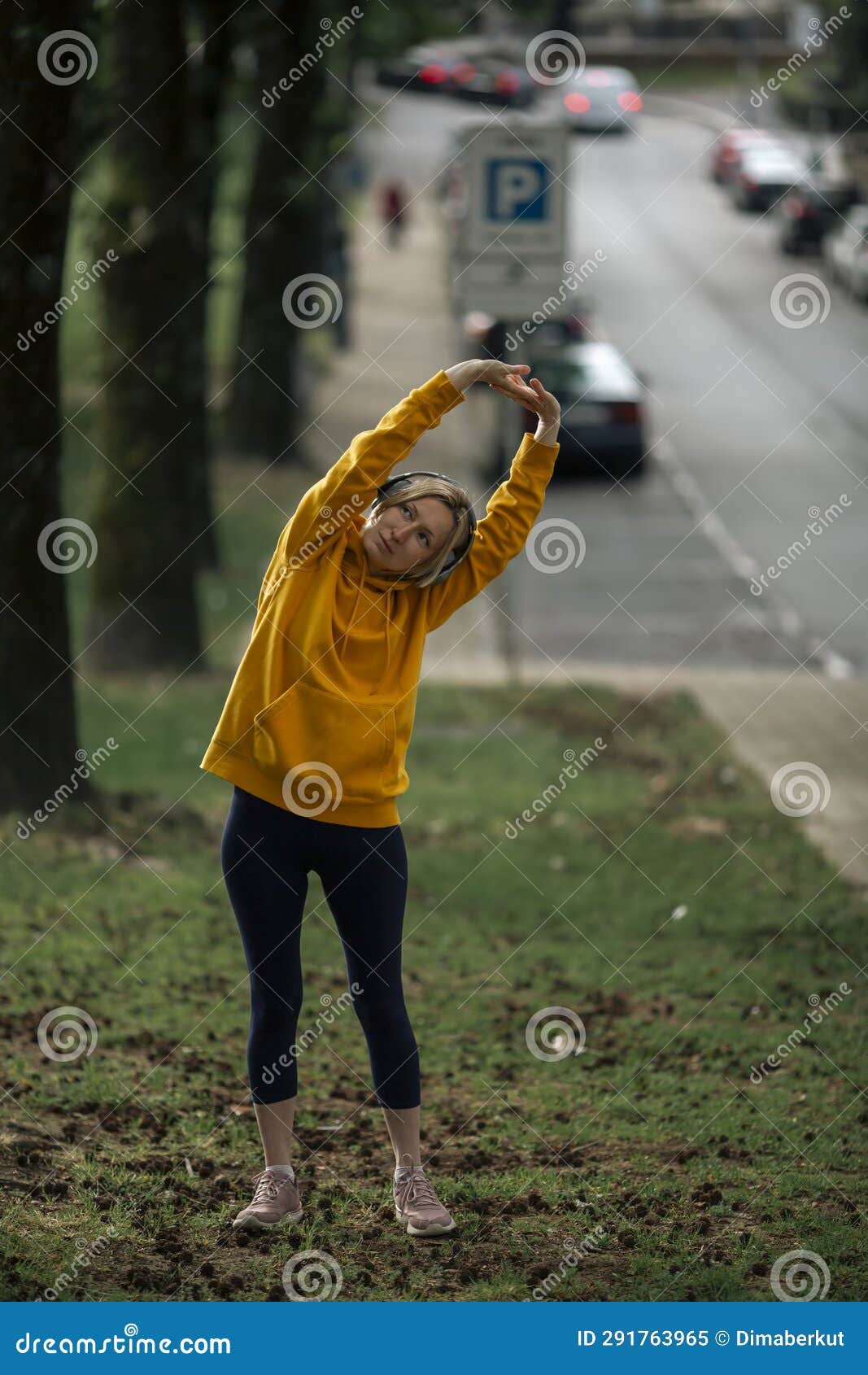 A Woman Wearing Headphones Warms Up before a Jog in the Park. Stock ...