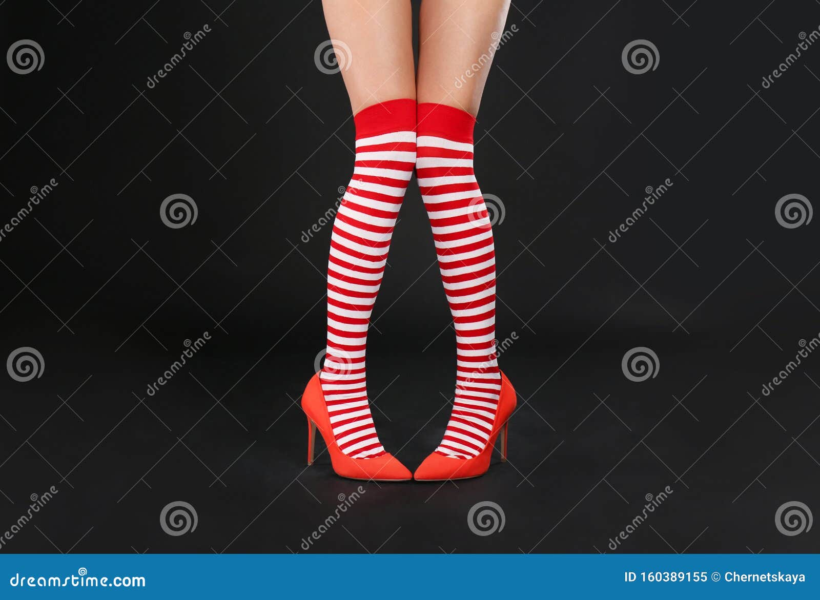 Woman Wearing High Heeled Red Shoes and Festive Socks Against Black ...