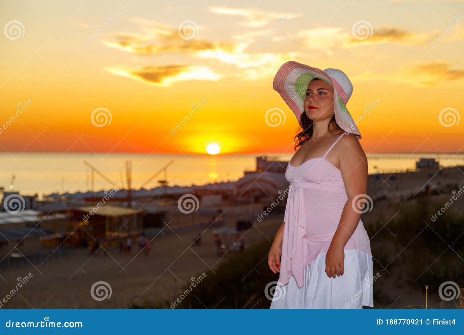 woman in a white dress on a background of the sea at sunset.