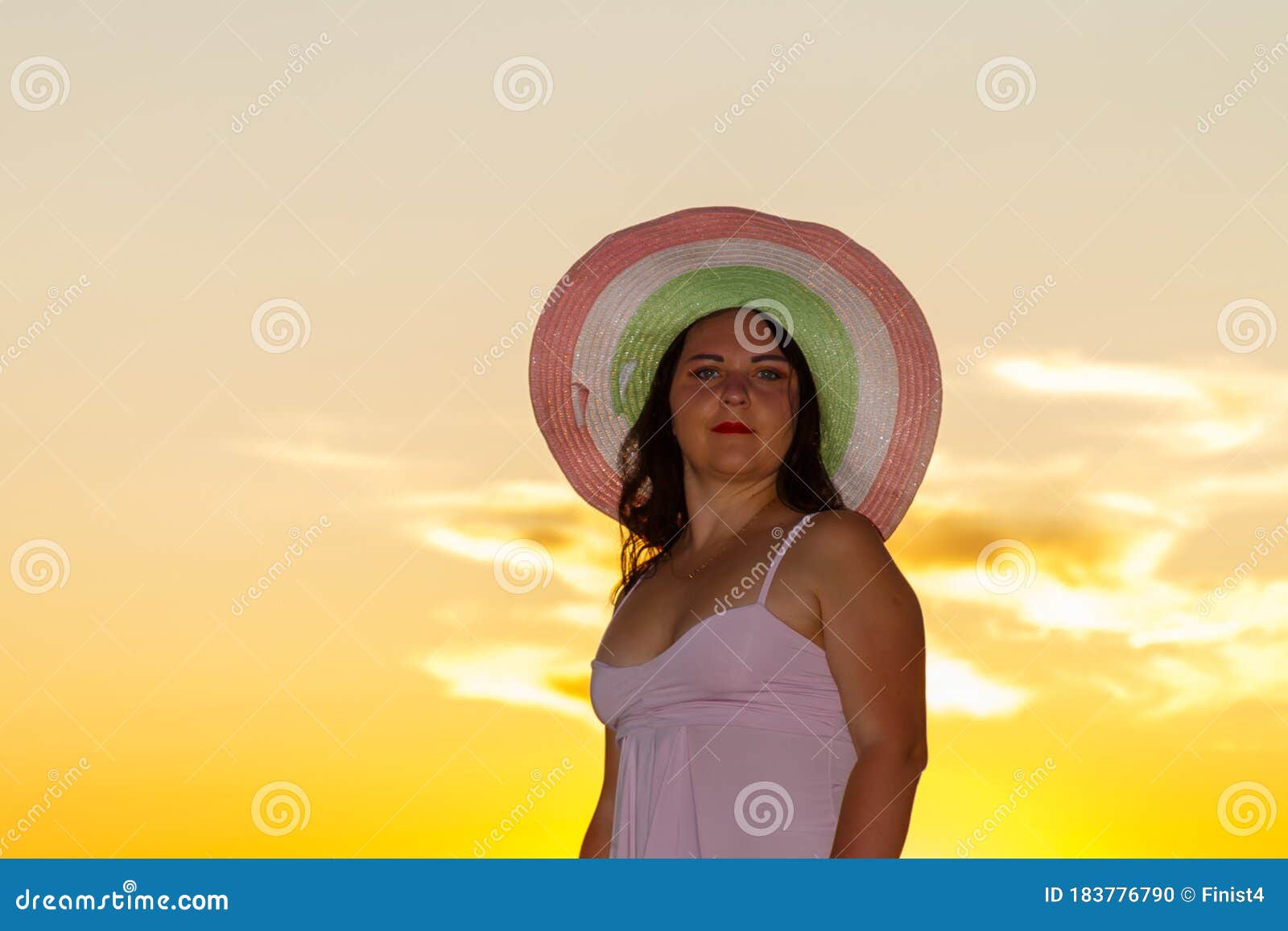 woman in a white dress and hat on a background of a sunset sky