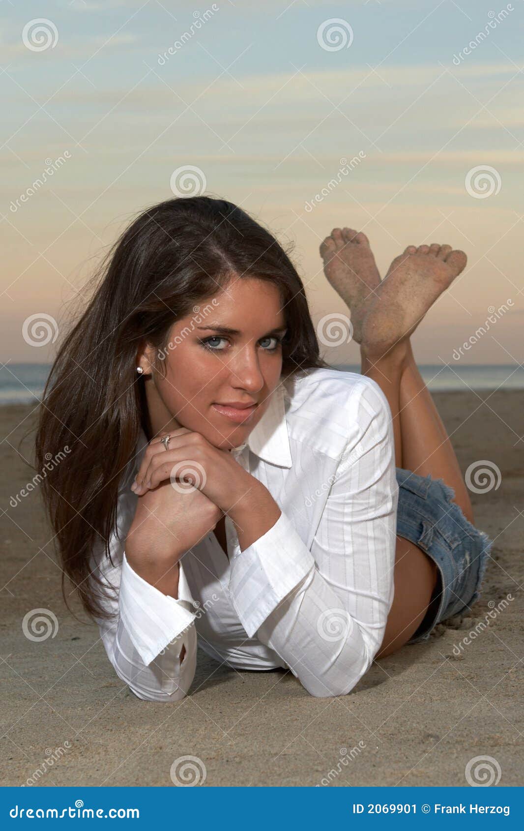 woman in white tailored top lying on stomach with ankles crossed