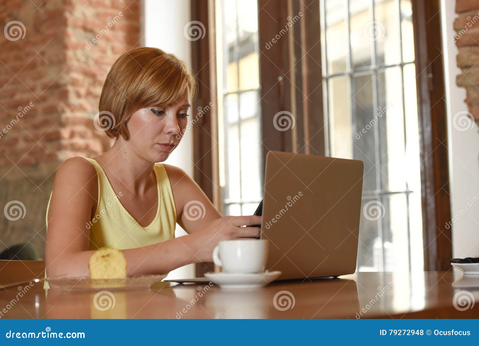 woman working busy at coffee shop with laptop computer using mobile phone