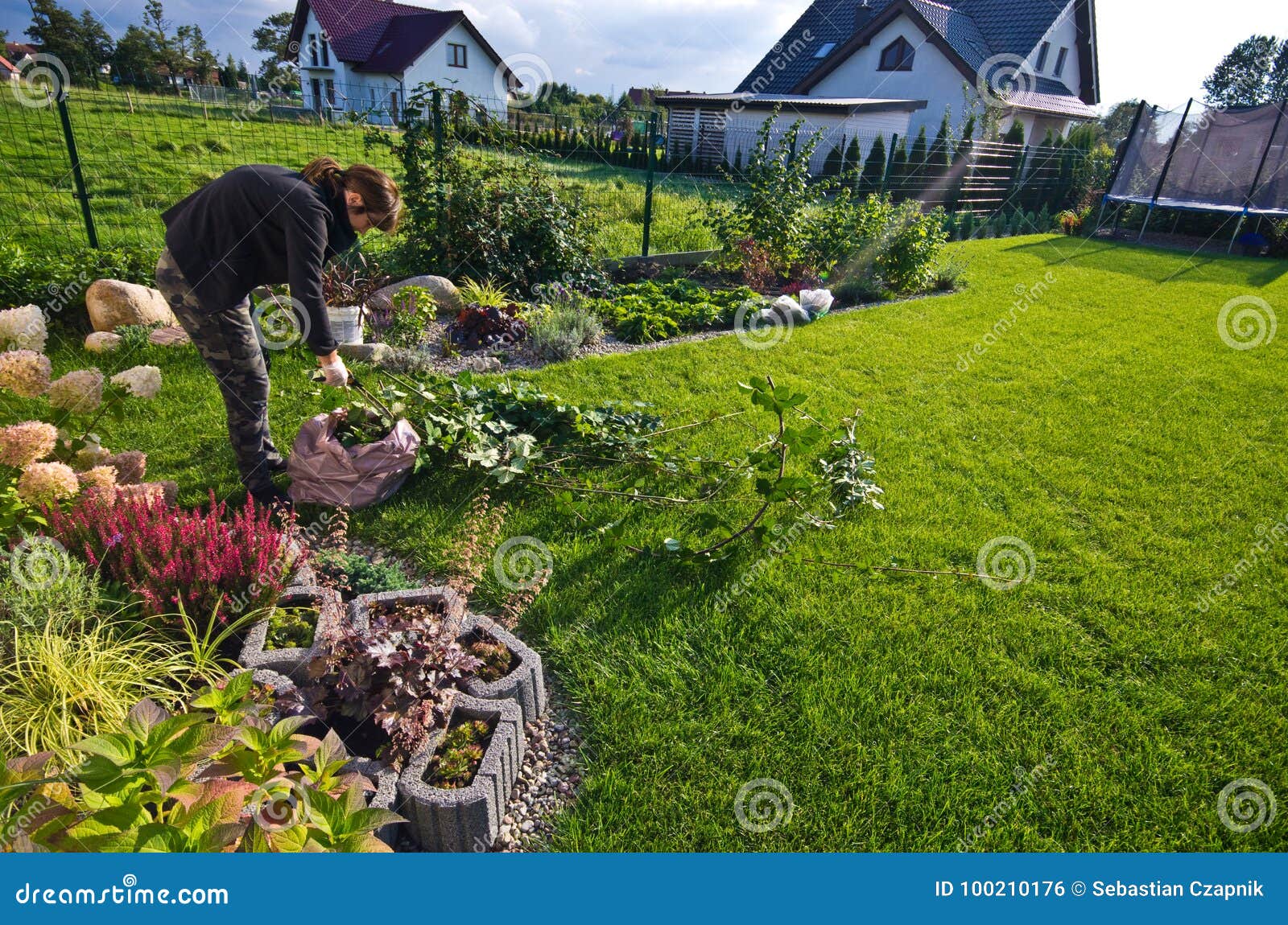 woman working in a garden, cutting excess twigs of plants