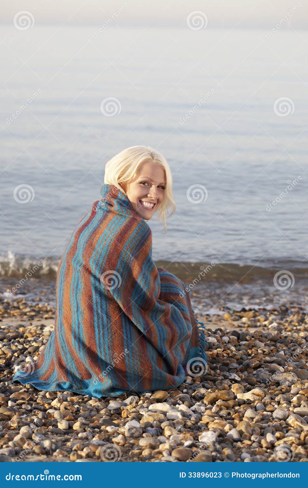 Woman Wrapped In Blanket Sitting At Beach Stock Image