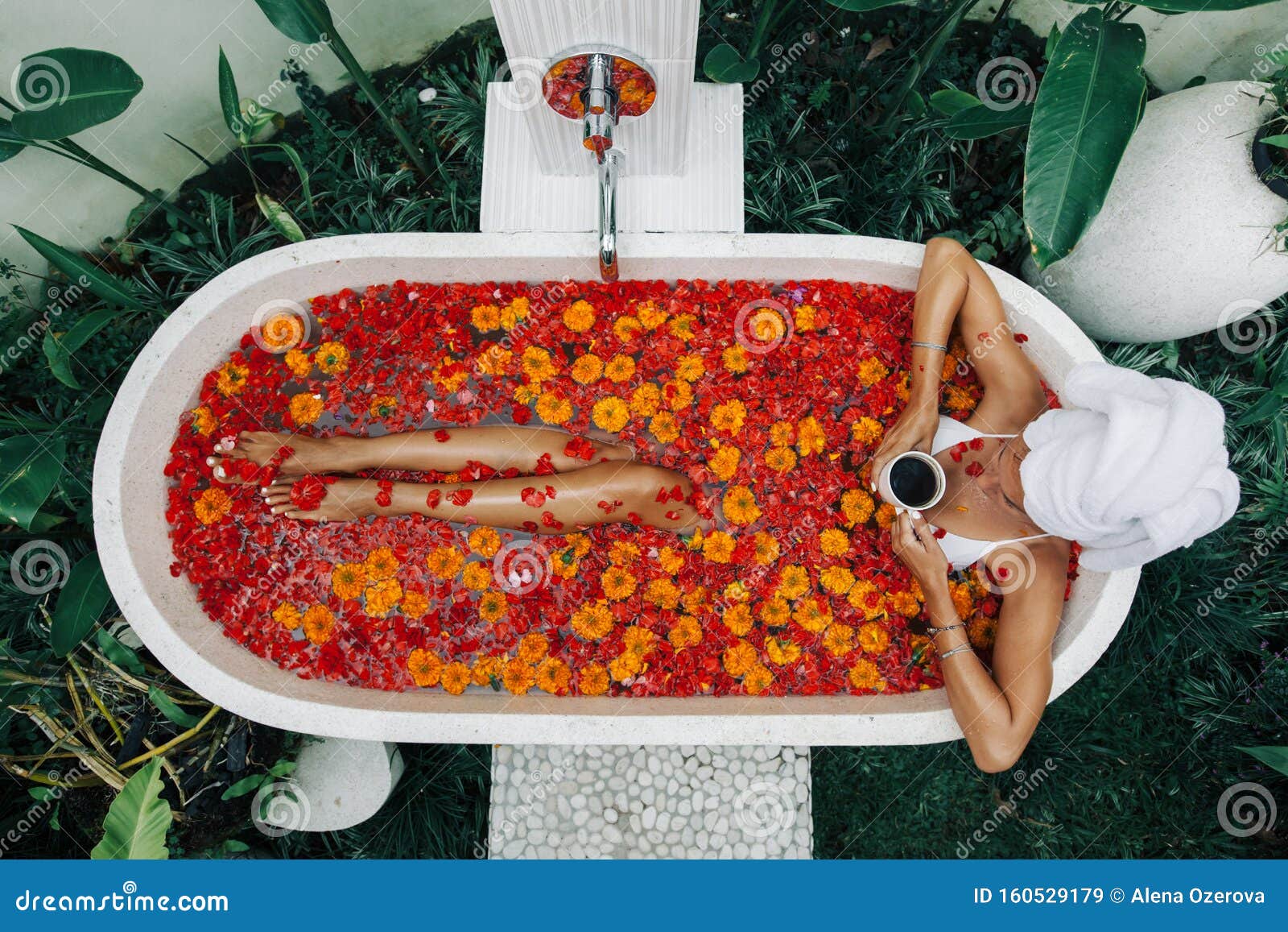 woman relaxing in outdoor bath with flowers in bali spa hotel