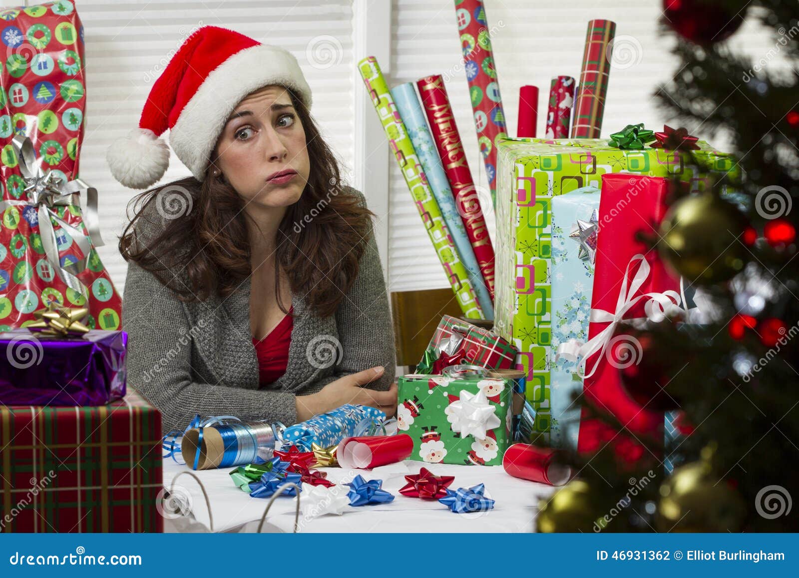 woman wrapping christmas presents, looking exhausted.