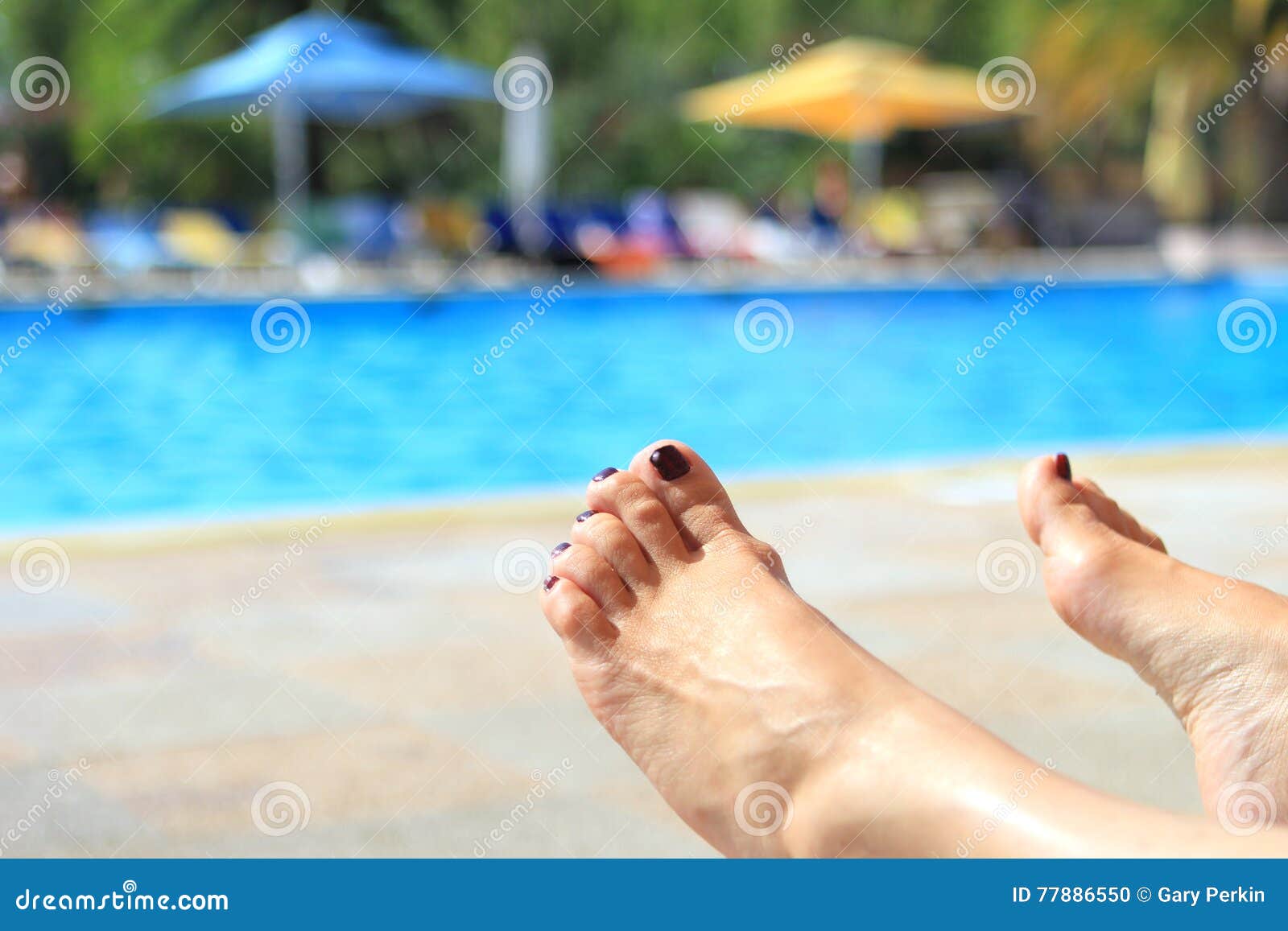 Woman& x27 πόδια του s με τη θολωμένη ηλιόλουστη πισίνα στο υπόβαθρο