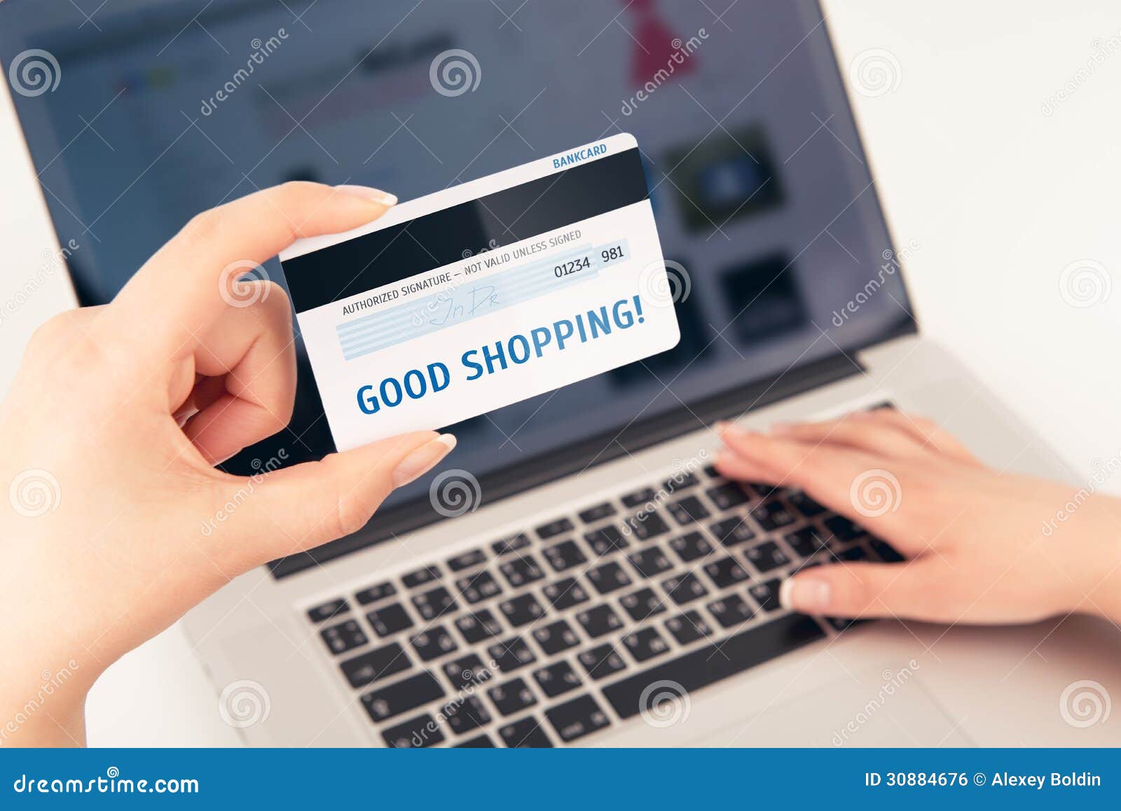 womans hand holding a bank card over a laptop.