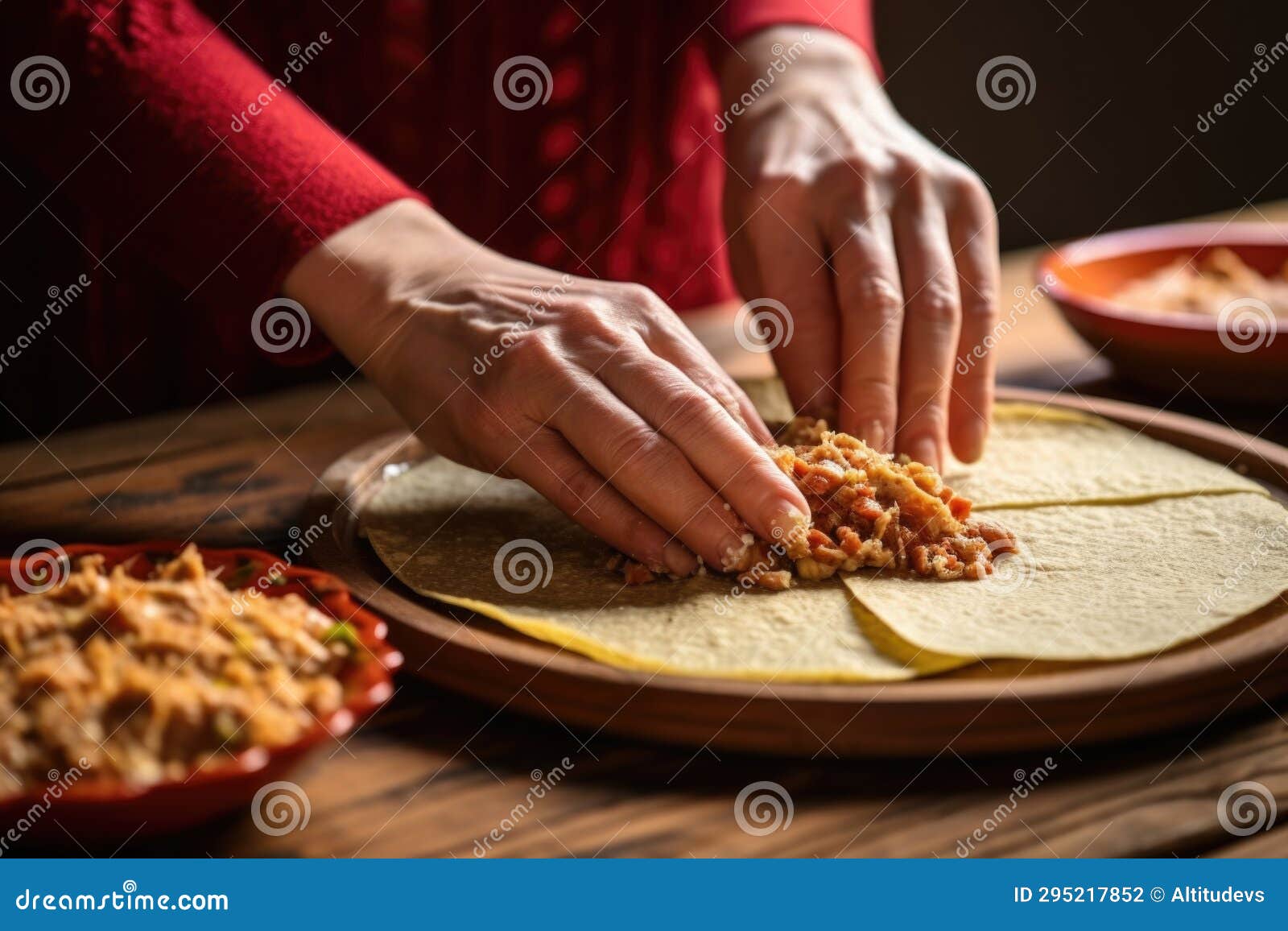 Womans Hand Spreading Refried Beans on Tortilla for Enchilada Stock