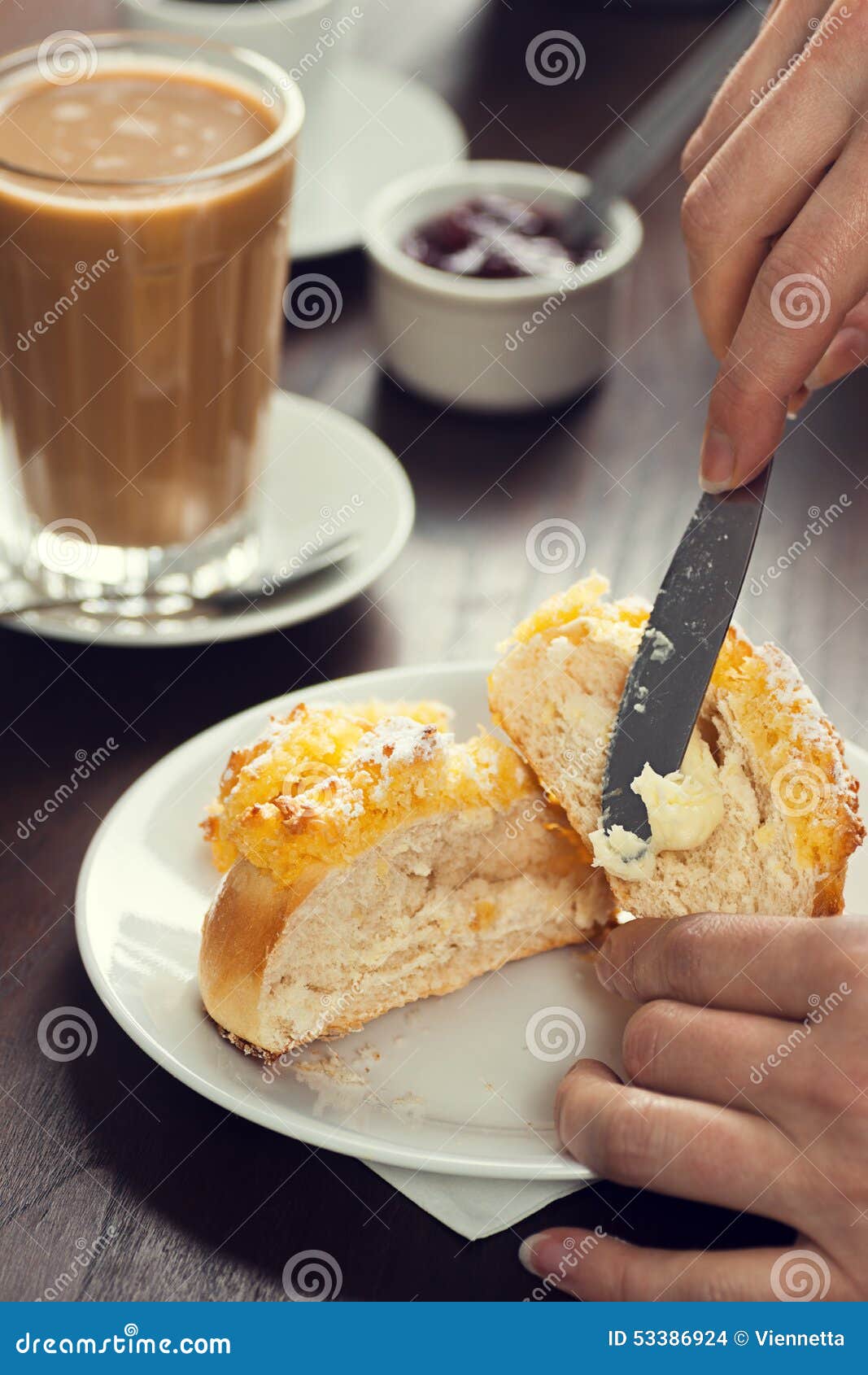 womans hand spreads butter on pÃÂ£o de deus roll