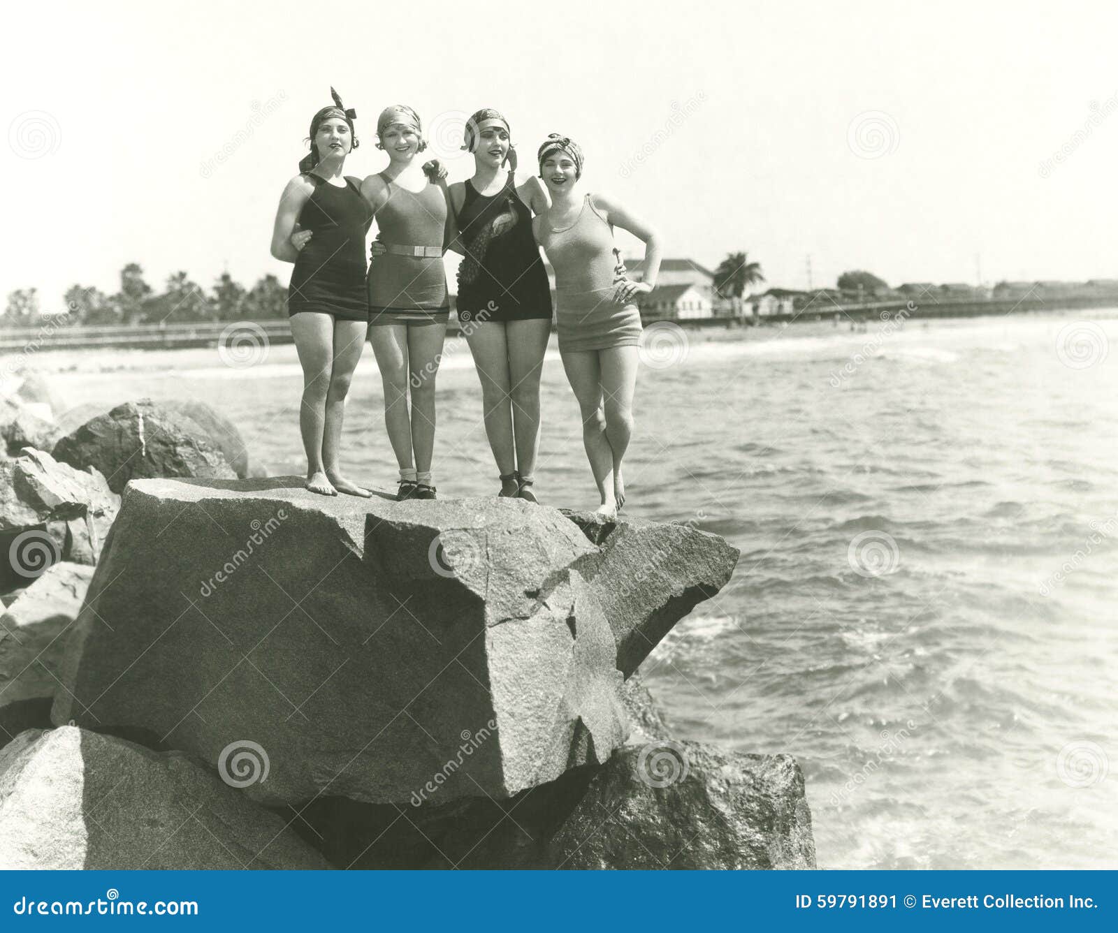 women in bathing suits posing on rock