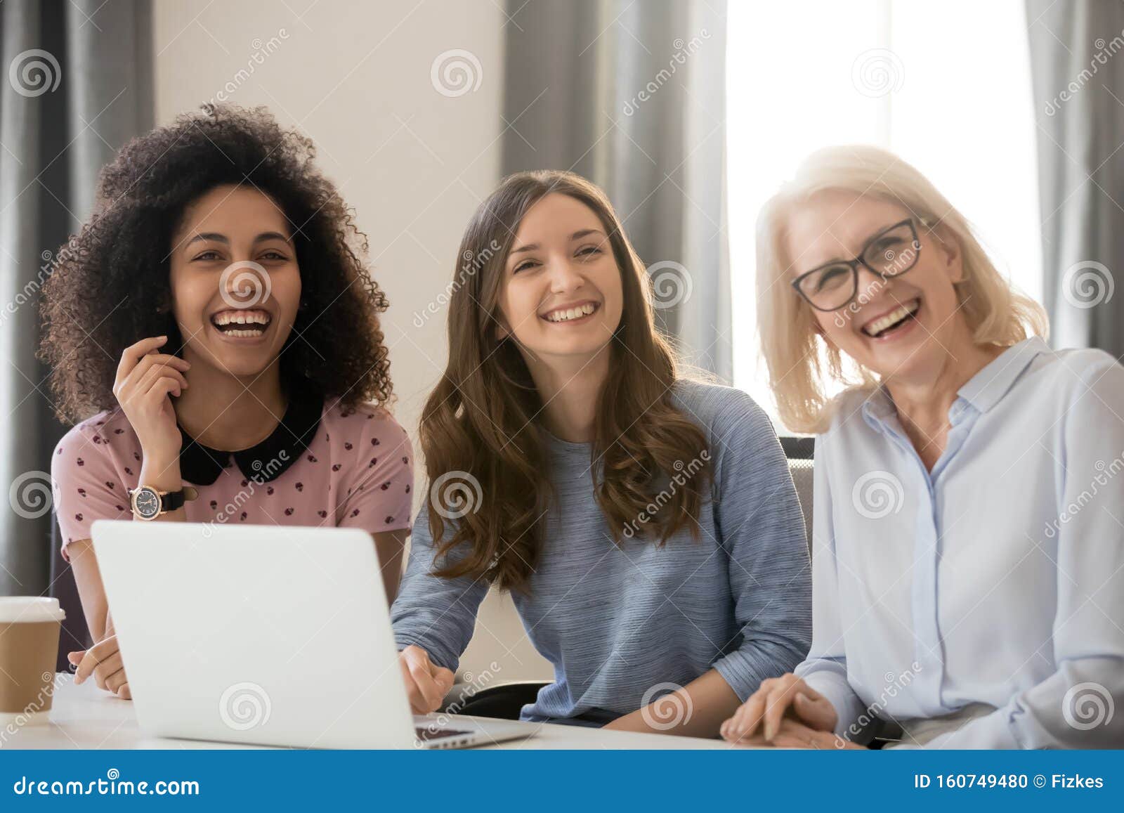 women different ethnicity and ages looking away laughing at workplace