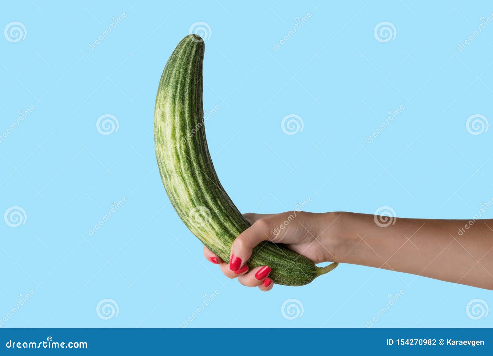 Women Hand Holding Cucumber Like a Man`s Penis on Blue Background picture