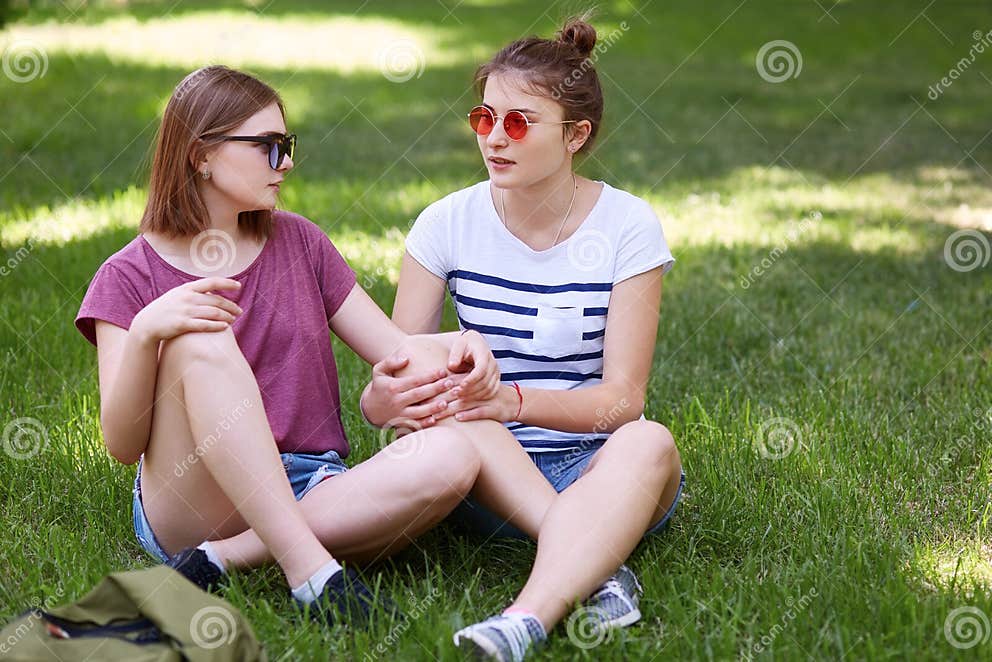 Women Lesbians Have Fun Together While Sit Crossed Legs On Green Grass Look With Love At Each