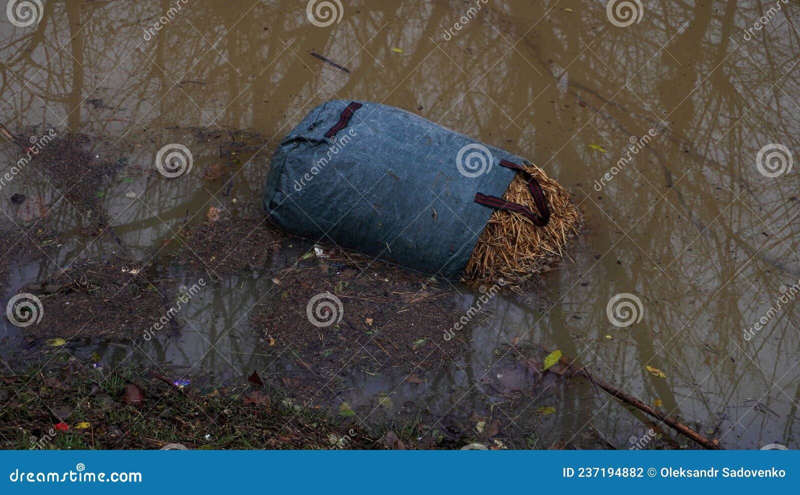 a women's bag filled with straw lies in the water on