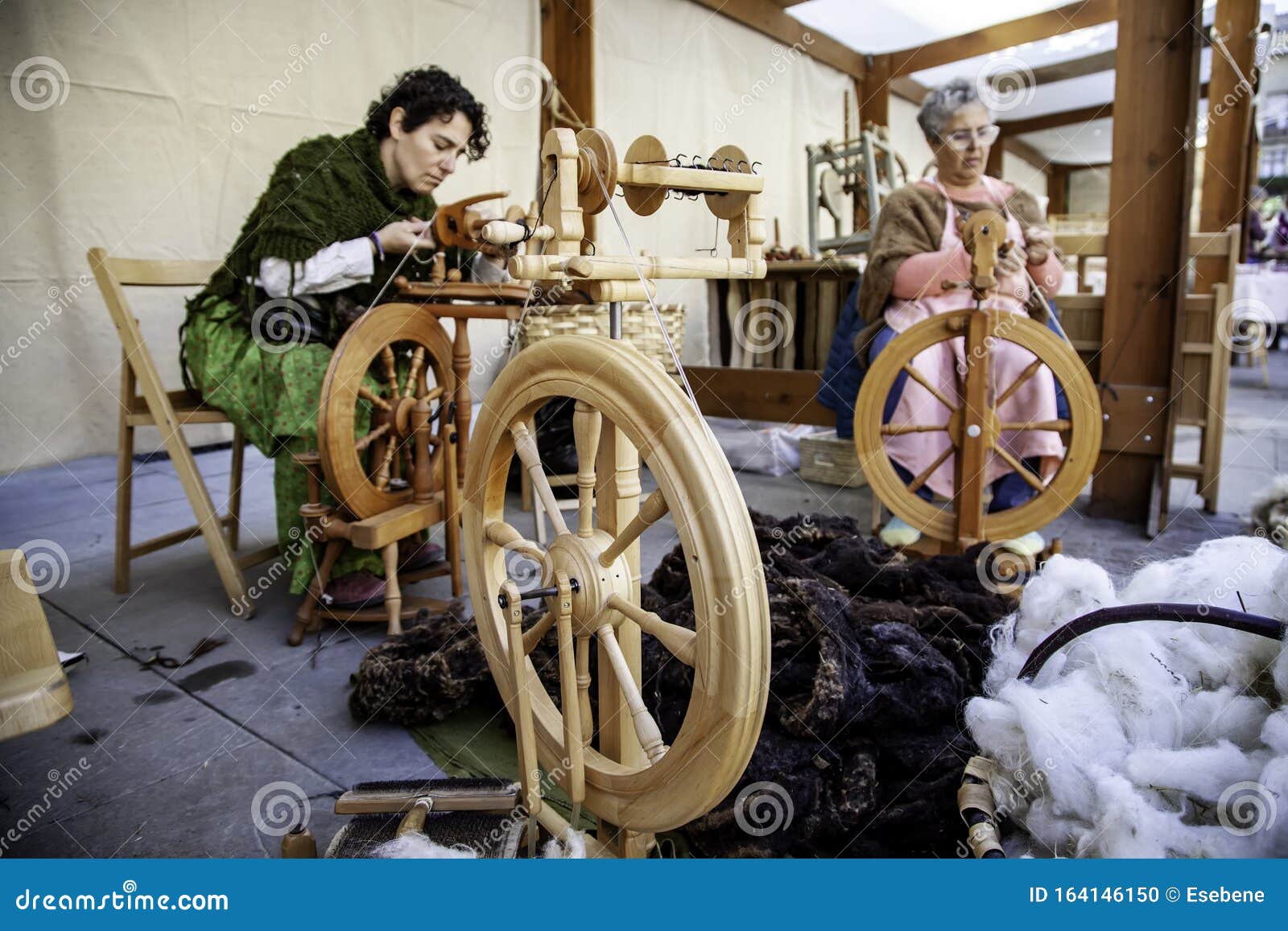Women Spinning Thread with a Wooden Spinning Wheel Stock Photo
