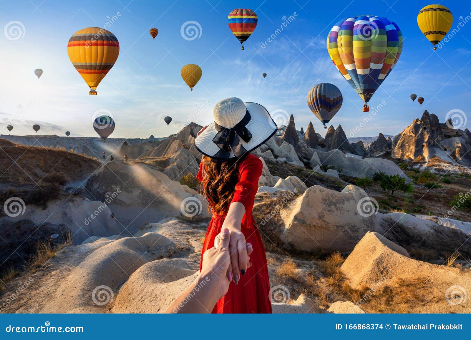 women tourists holding man`s hand and leading him to hot air balloons in cappadocia, turkey.