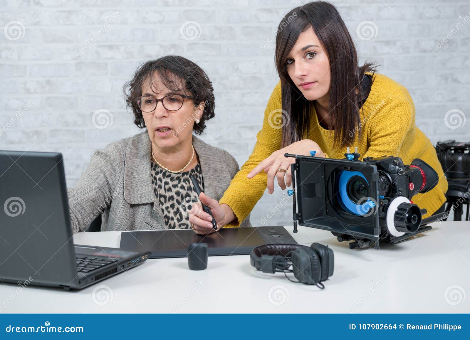 Woman Video Editor and Young Assistant Using Graphic Tablet Stock Photo