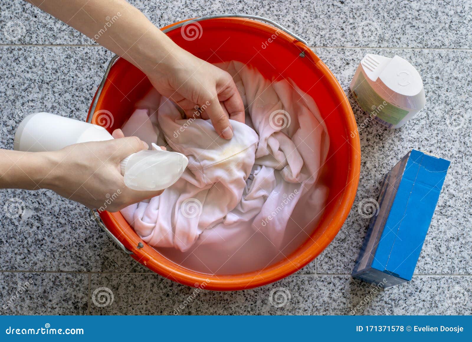 womens hands washing dirty stained white shirts with a stain remover from a spray detergent bottle for yellow sweat stains in a