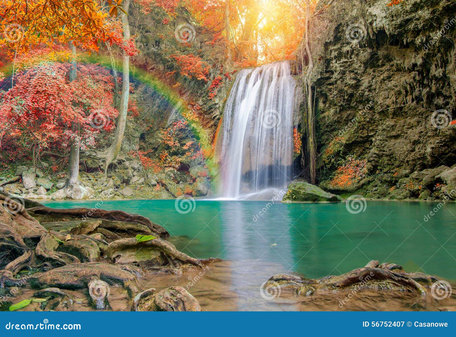 wonderful waterfall with rainbows and red leaf in deep forest