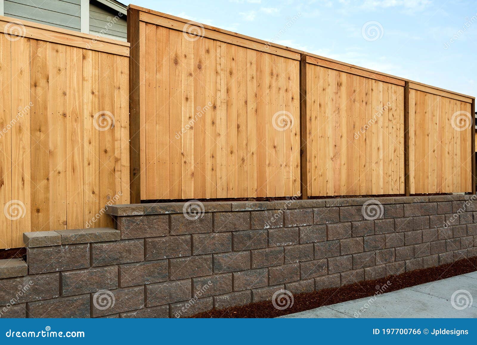 wood fence on stone retaining wall on side of home