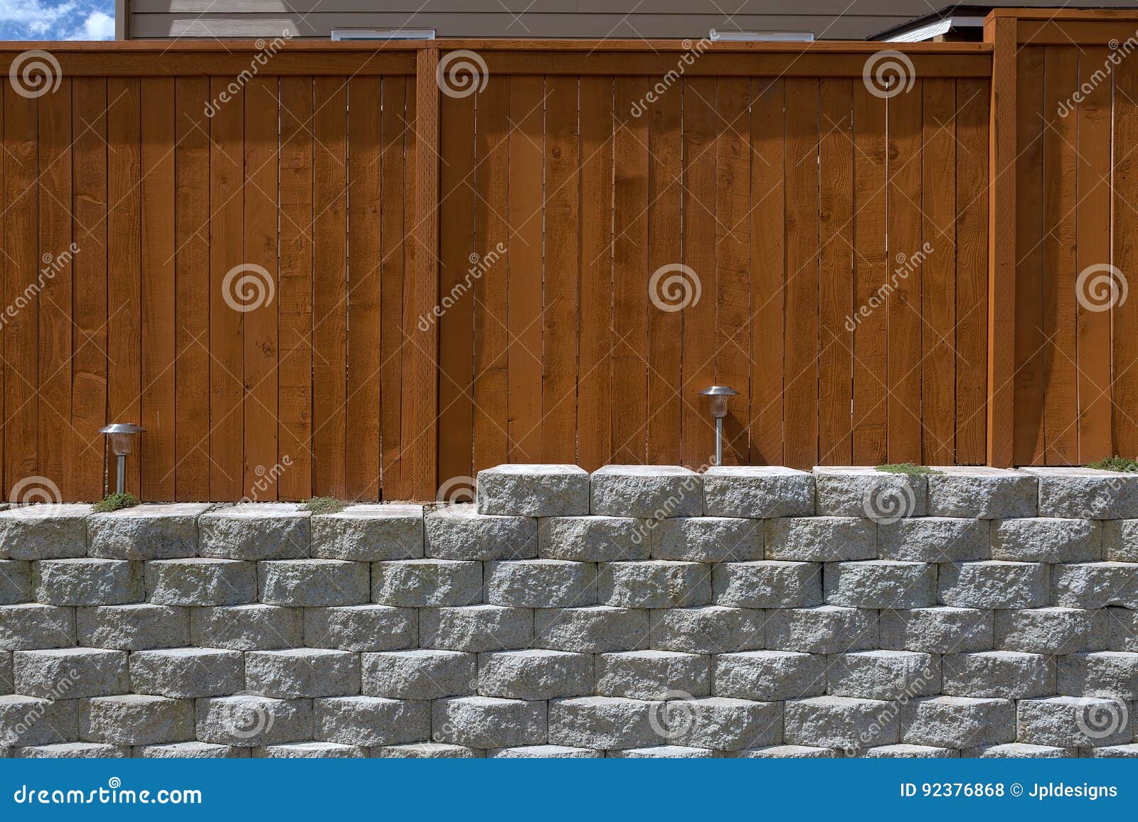 wood fencing on cement stack stone retaining wall