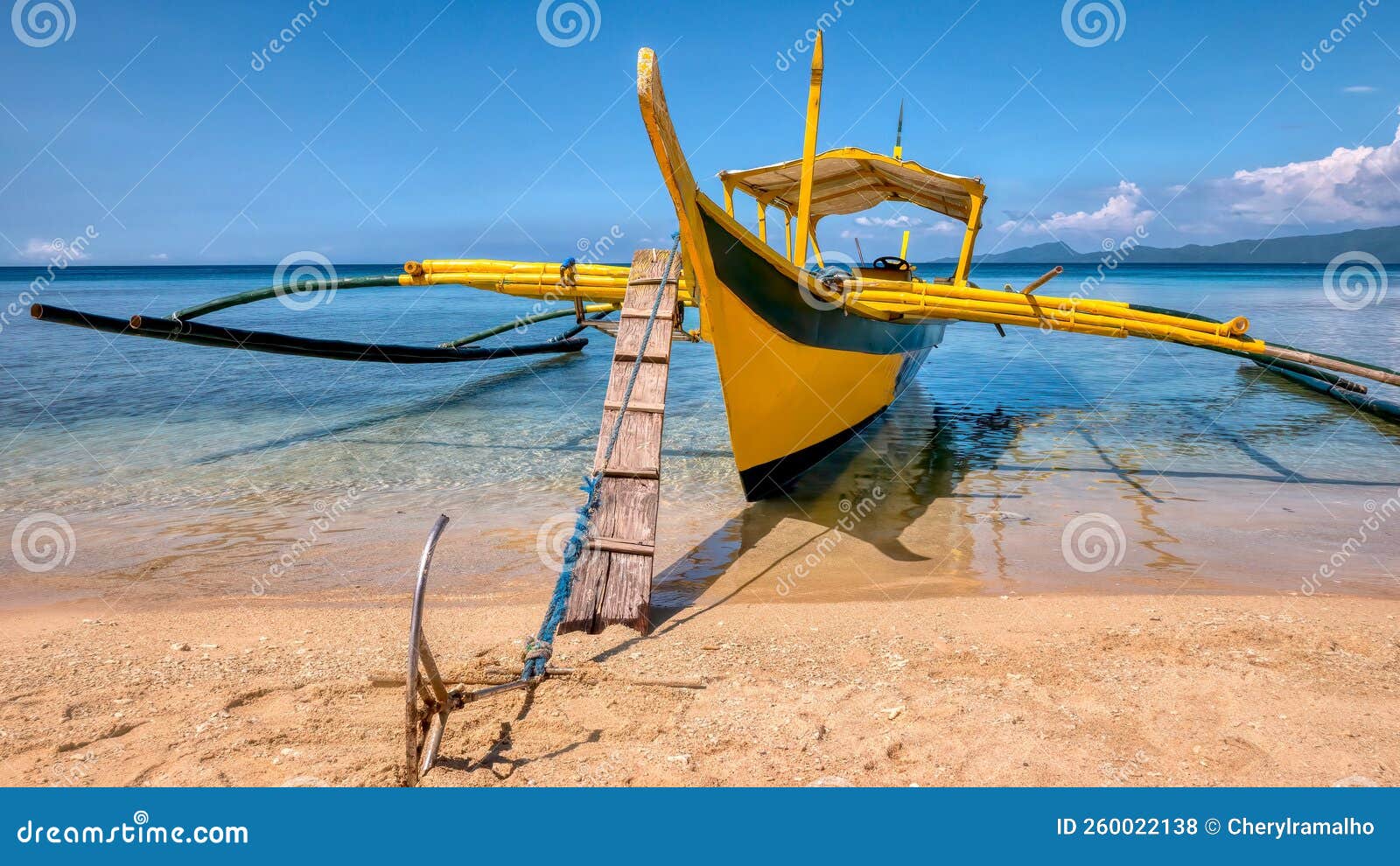 a wooden banca anchored on the beach of a tropical island in the philippines.