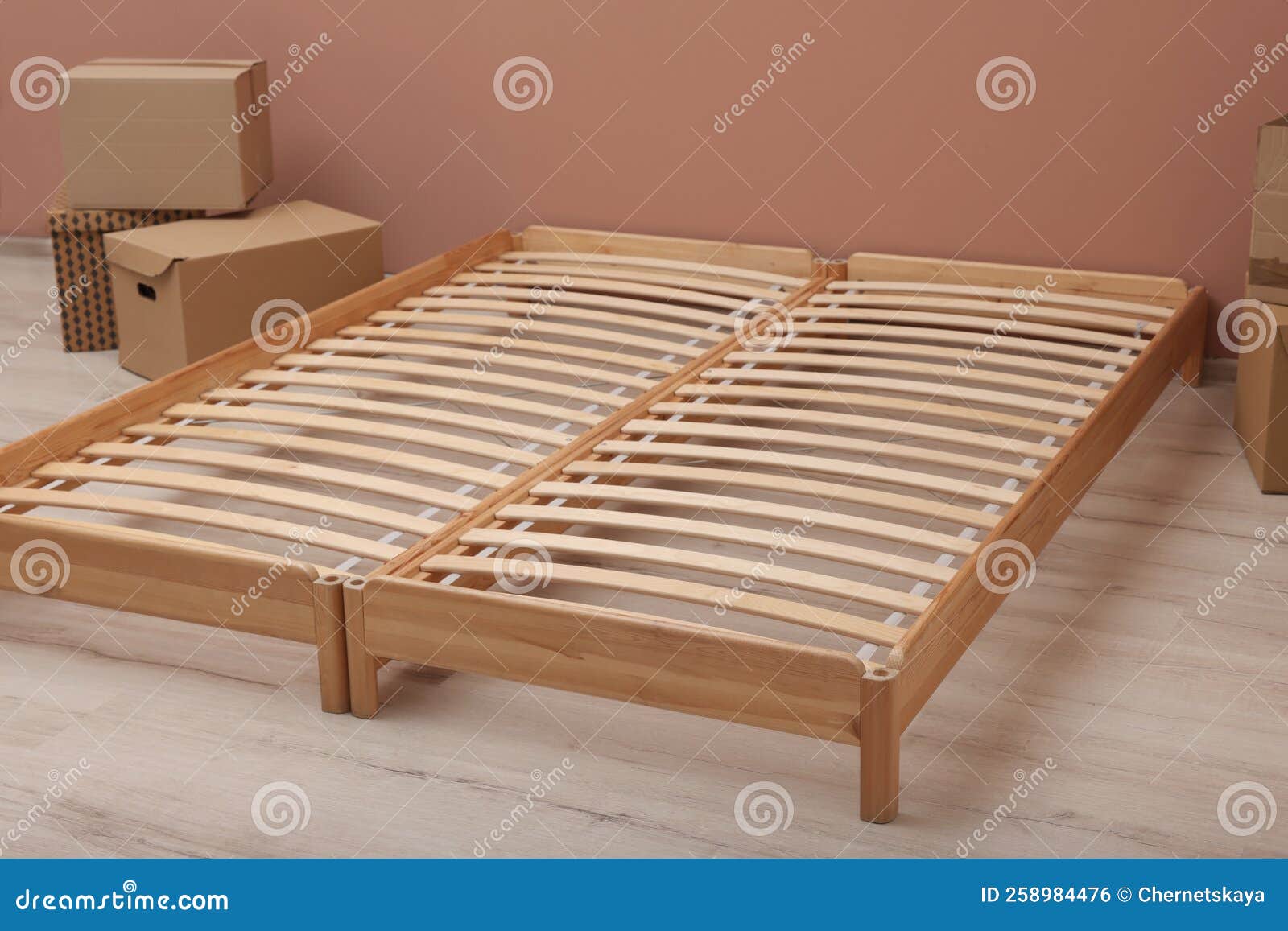 Wooden Bed Frame and Cardboard Boxes on Floor in Room Stock Photo