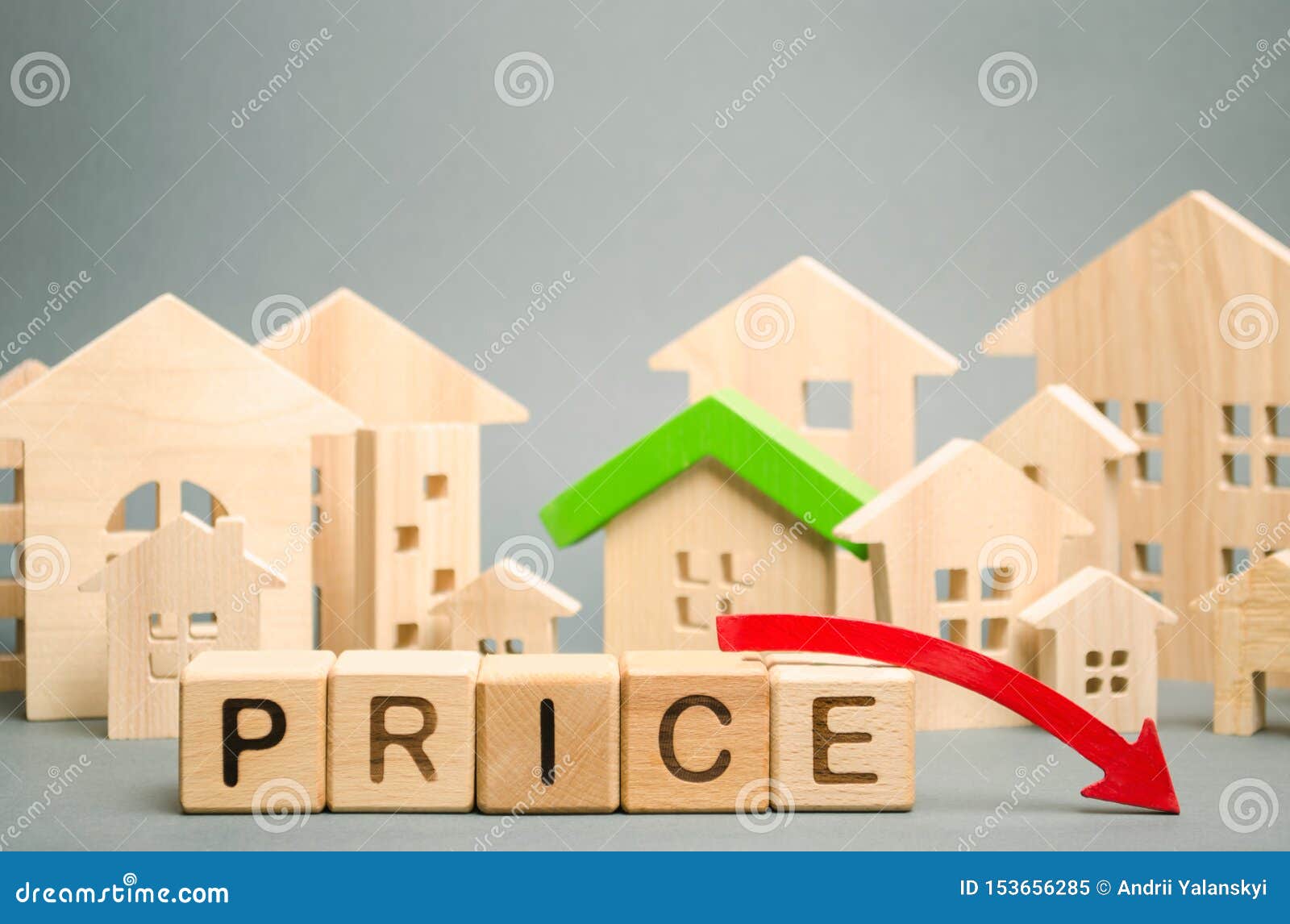 wooden blocks with the word price, down arrow and miniature houses. reduced housing prices. the fall and crisis of the real estate
