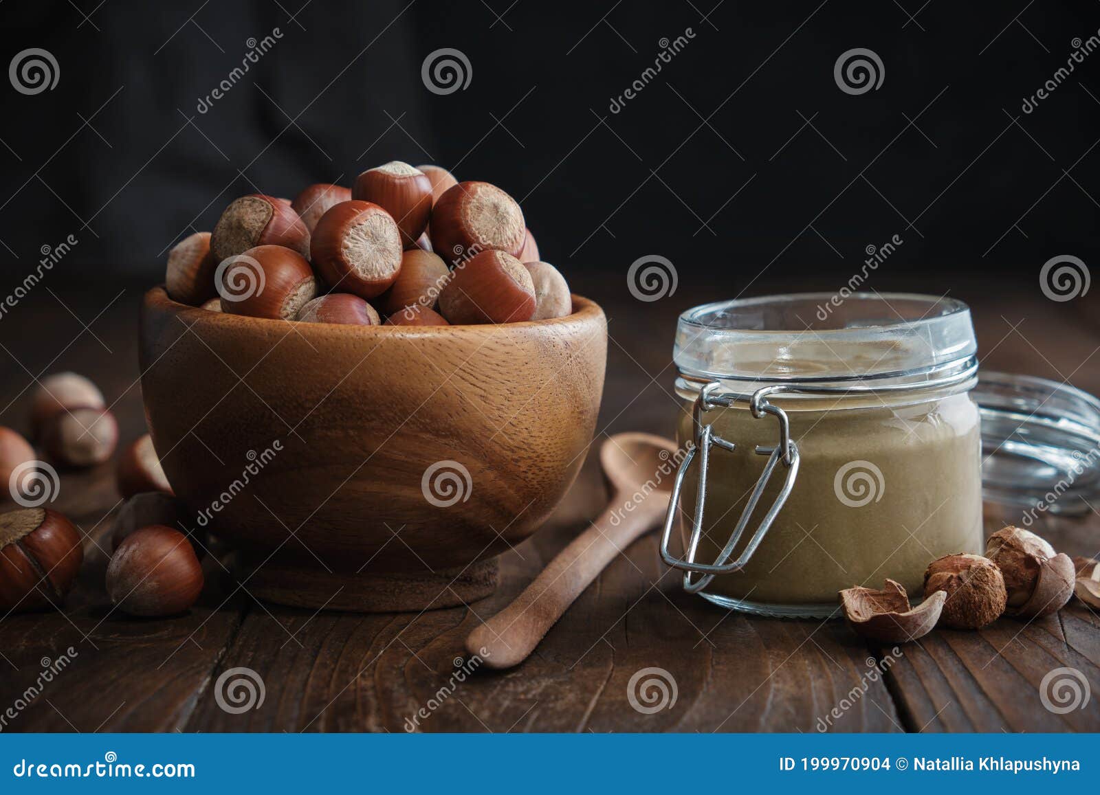 bowl of hazelnuts, glass jar of raw organic hazelnut butter or paste on kitchen table