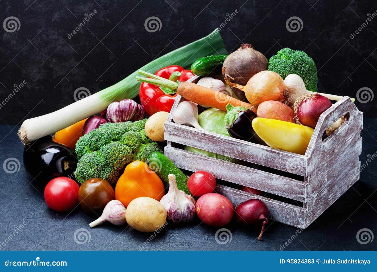 wooden box with autumn harvest farm vegetables and root crops on black kitchen table. healthy and organic food.