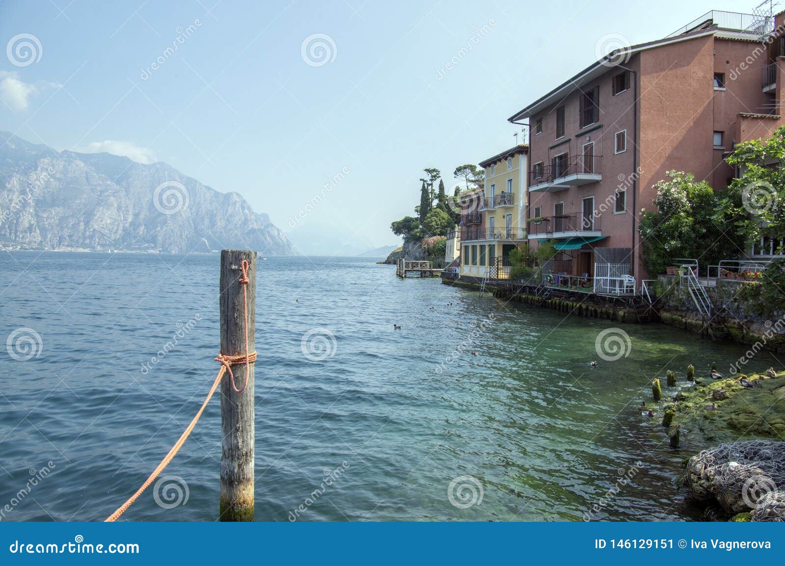 wooden bricole for boats in the water, lake lago di garda, morning light, mountains on the background