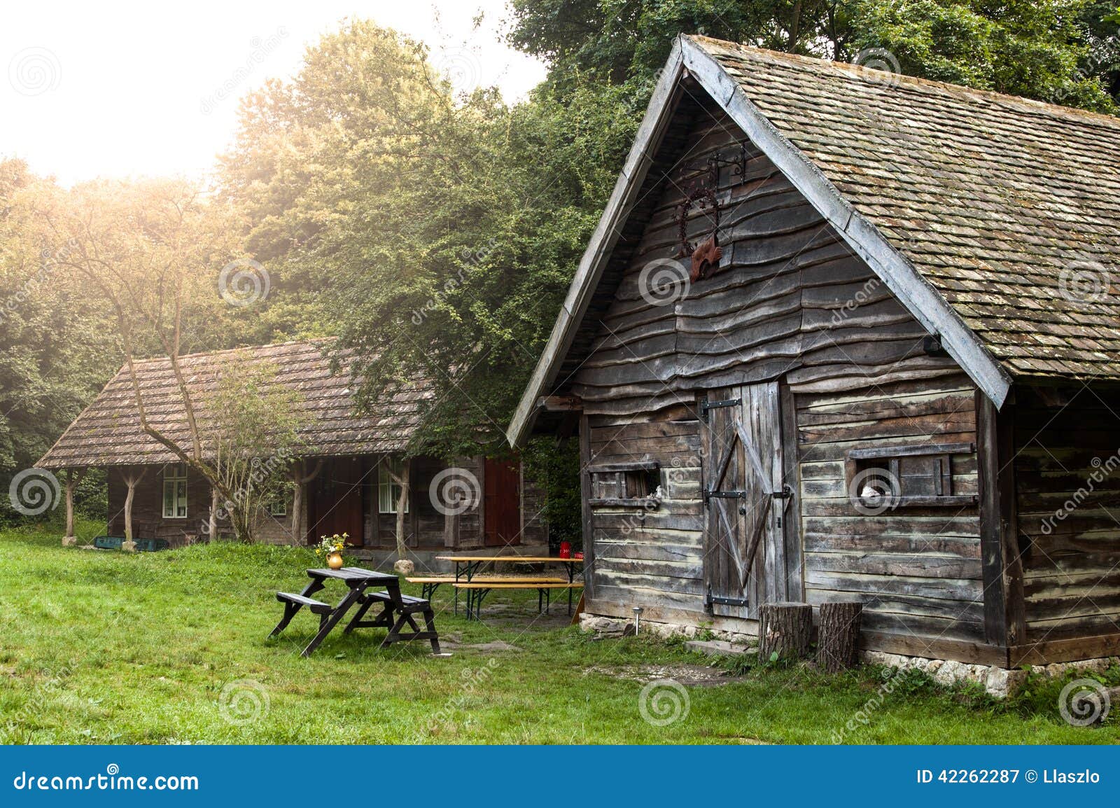 wooden house with tiled roof and old wooden shed with picnic table 