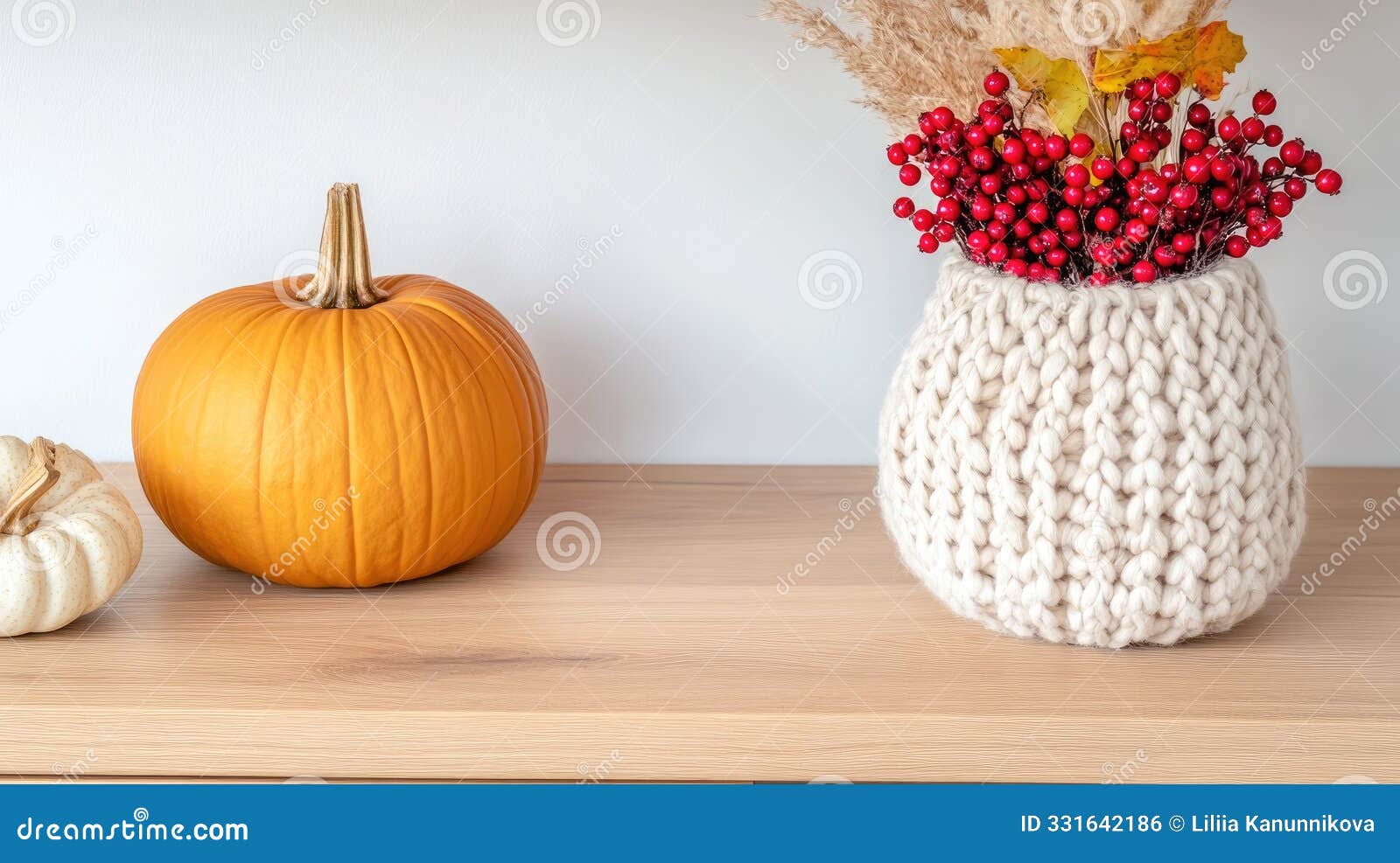 the wooden console displays wicker pumpkins, red berries, and candles, creating a minimalistic and inviting autumn