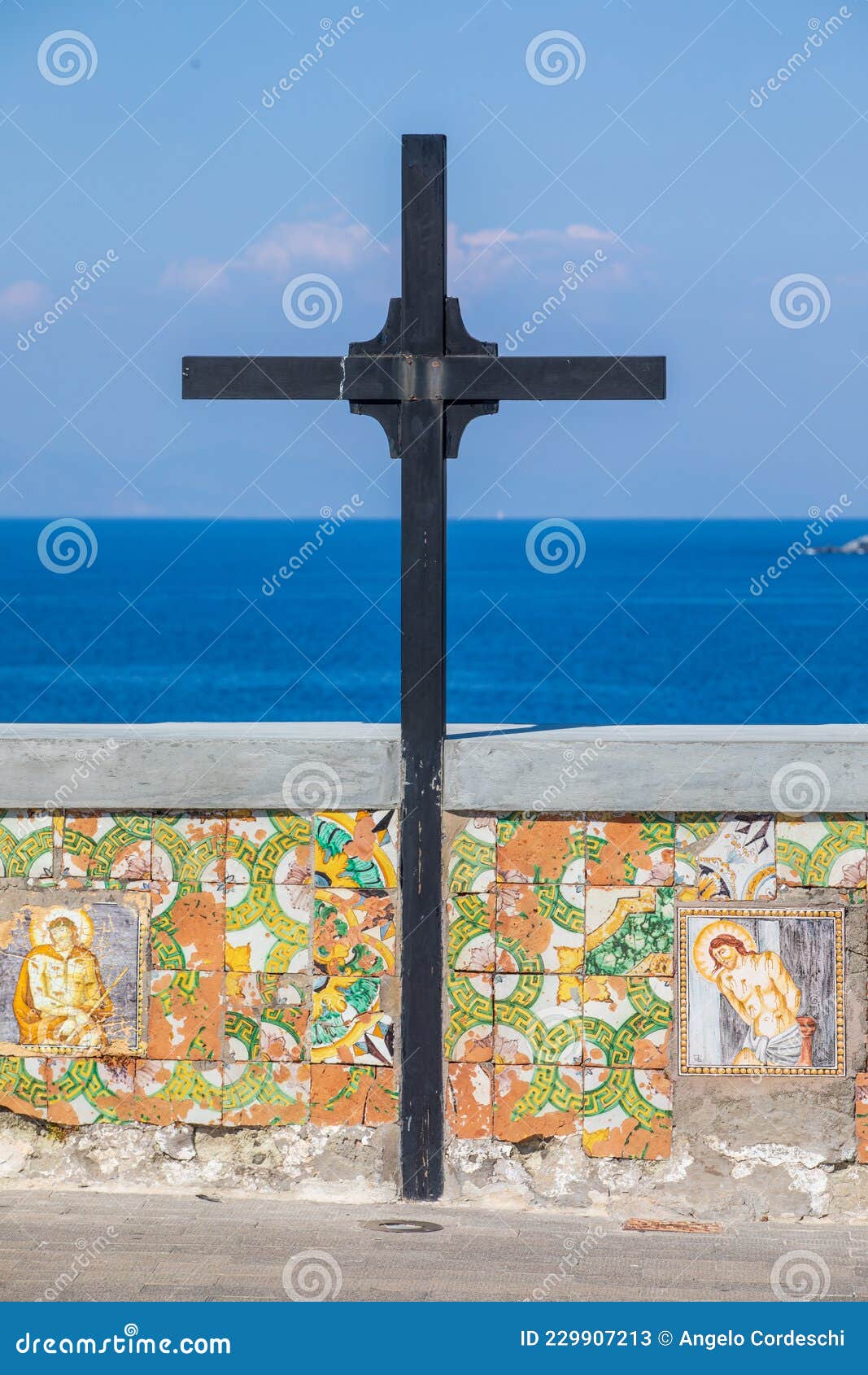 wooden cross with a low wall decorated with religious icons overlooking the sea. location: forio, soccorso church