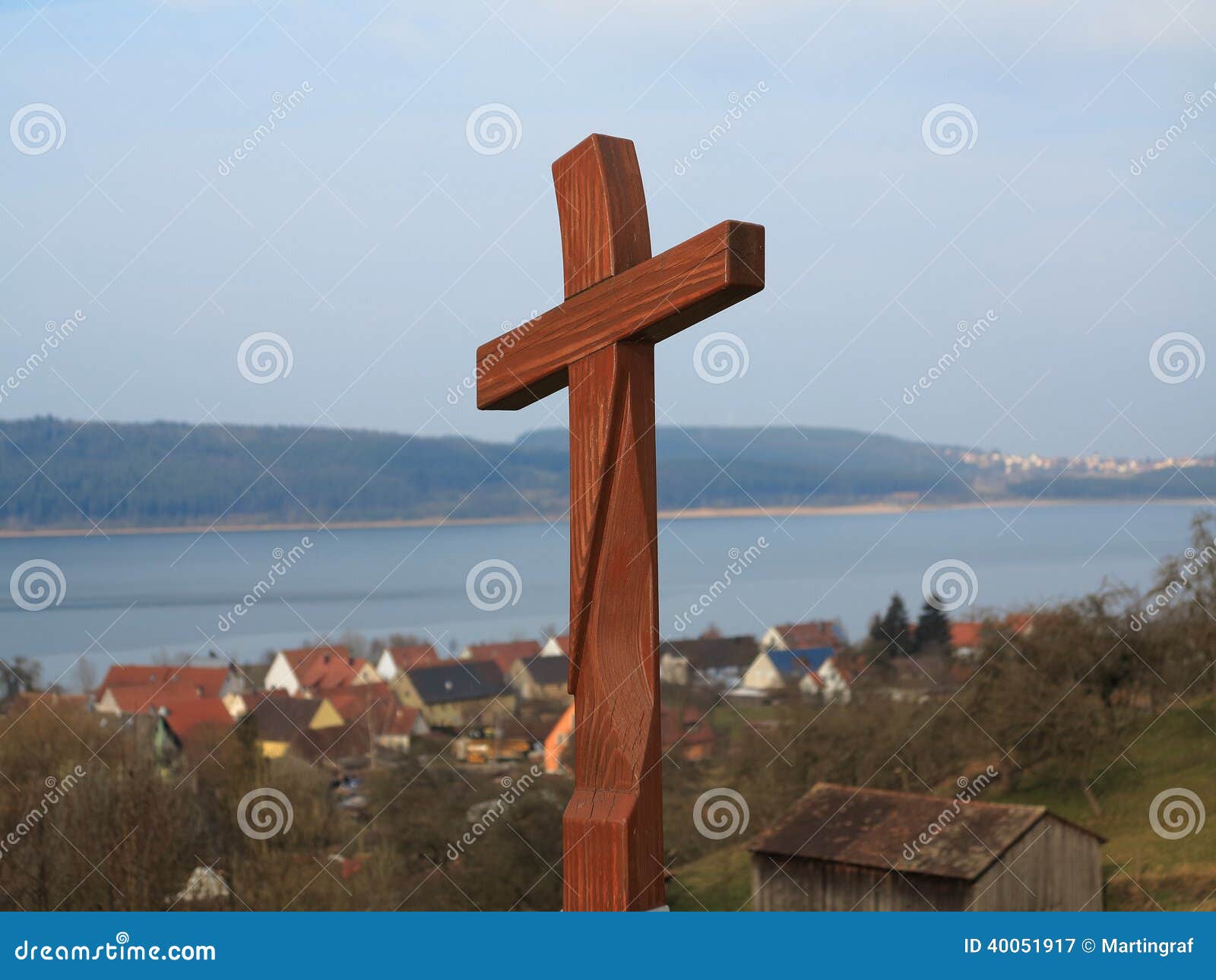 wooden cross at pilgrimage route by lakeside village