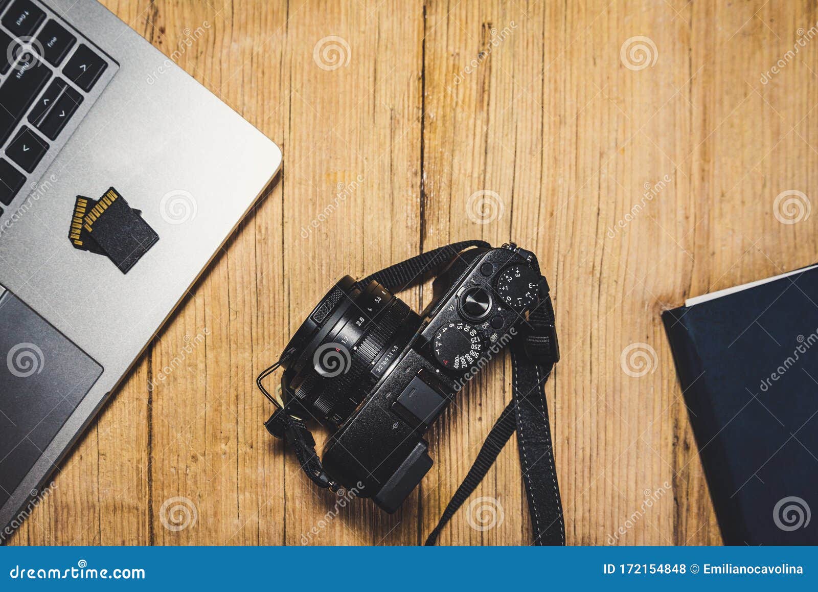 wooden desk table with camera, laptop, memory cards and clipboard.