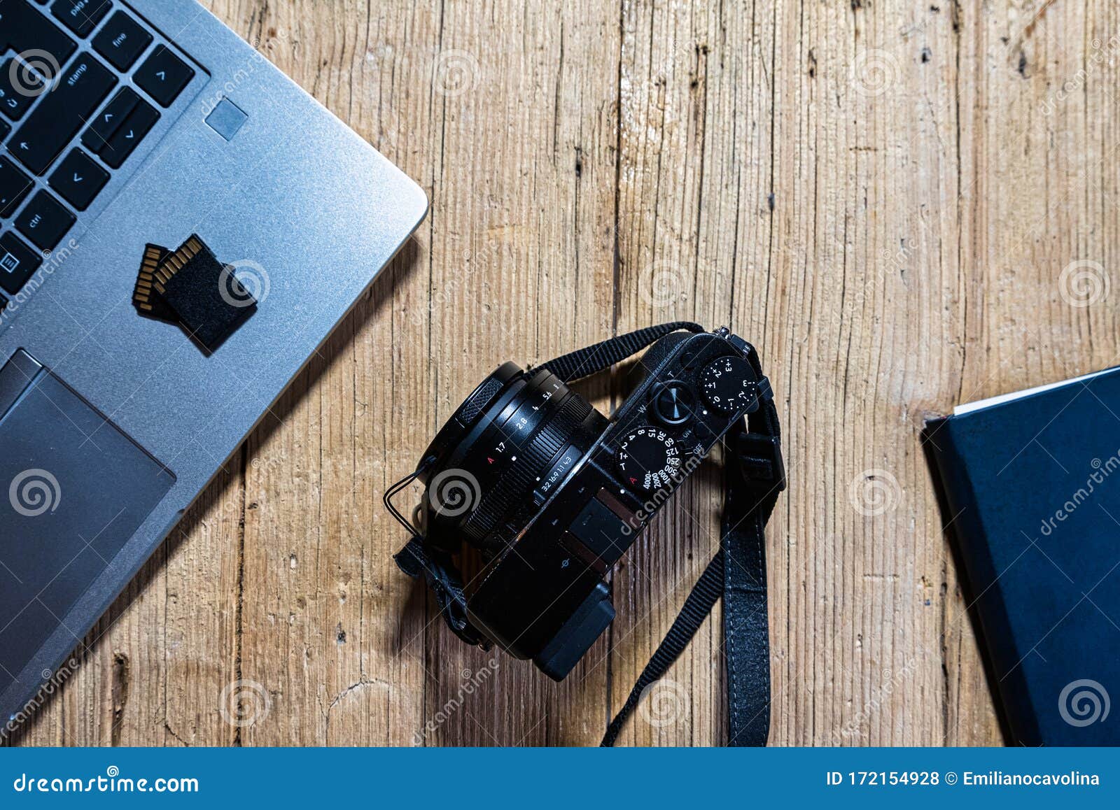 wooden desk table with camera, laptop, memory cards and clipboard.