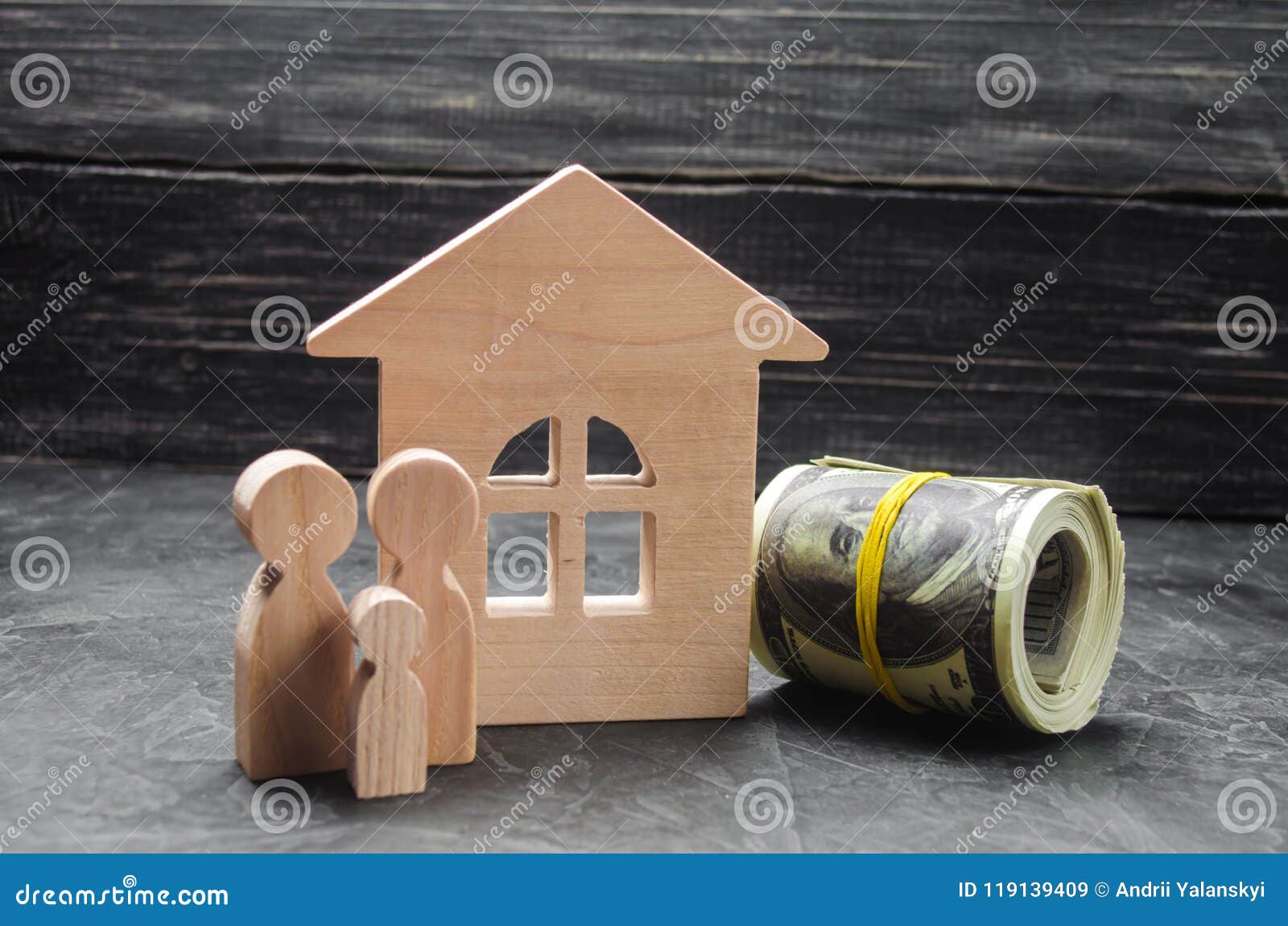 wooden figures of the family stand near a wooden house and collapsed money. buying and selling a house. good life, moving